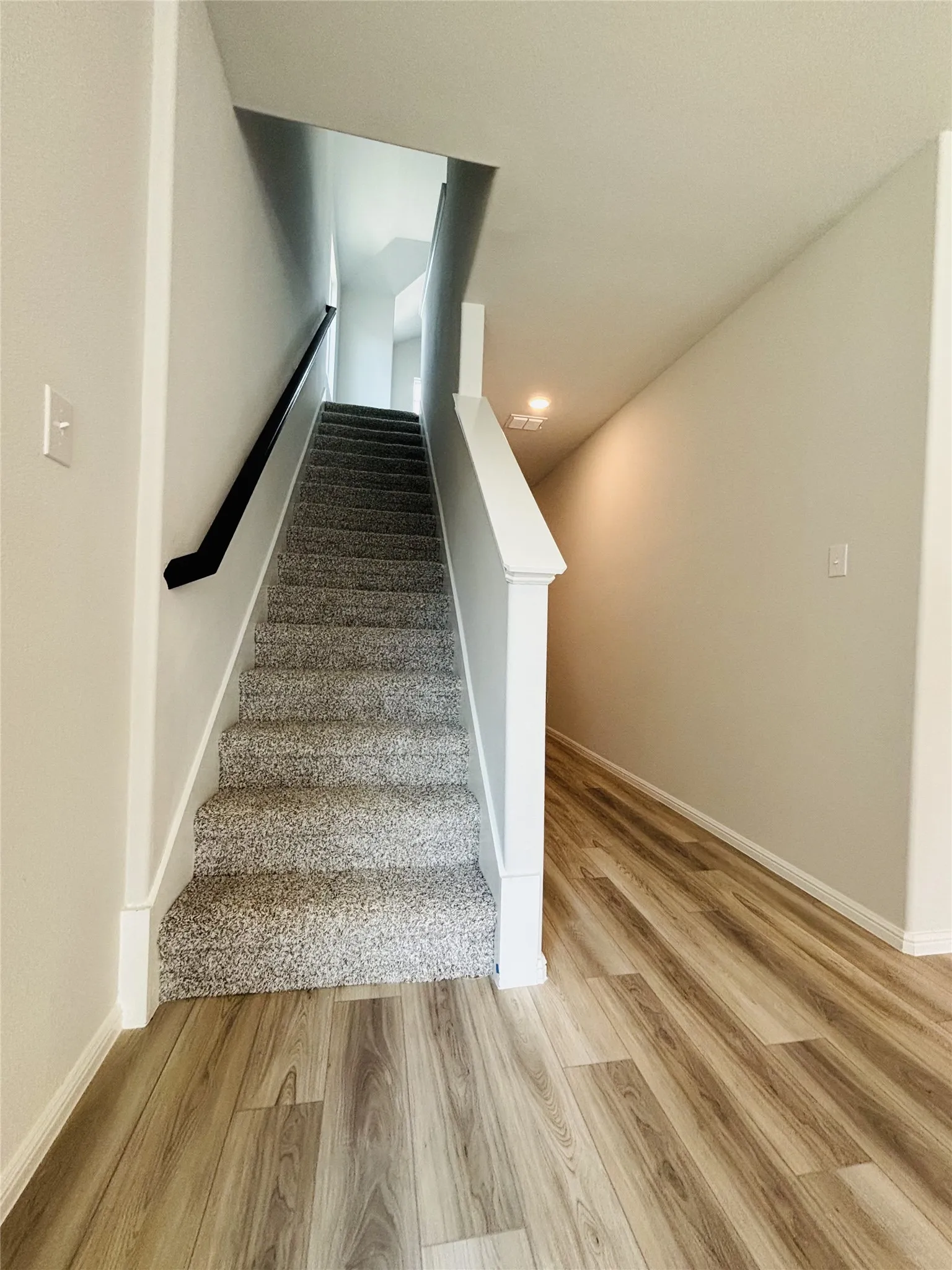 Stairs with wood finished floors and recessed lighting