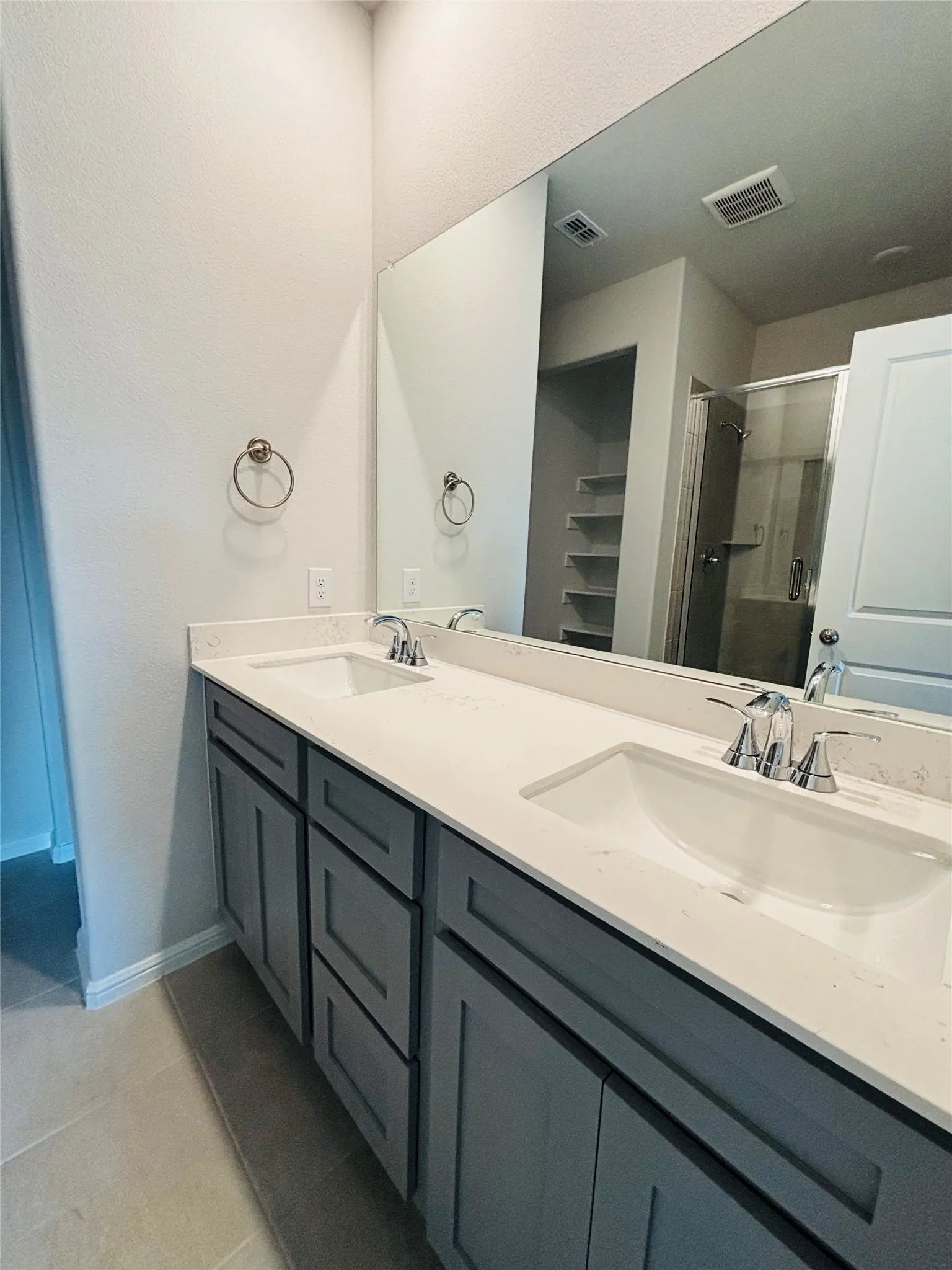 Full bath featuring tile patterned flooring, double vanity, and a shower stall