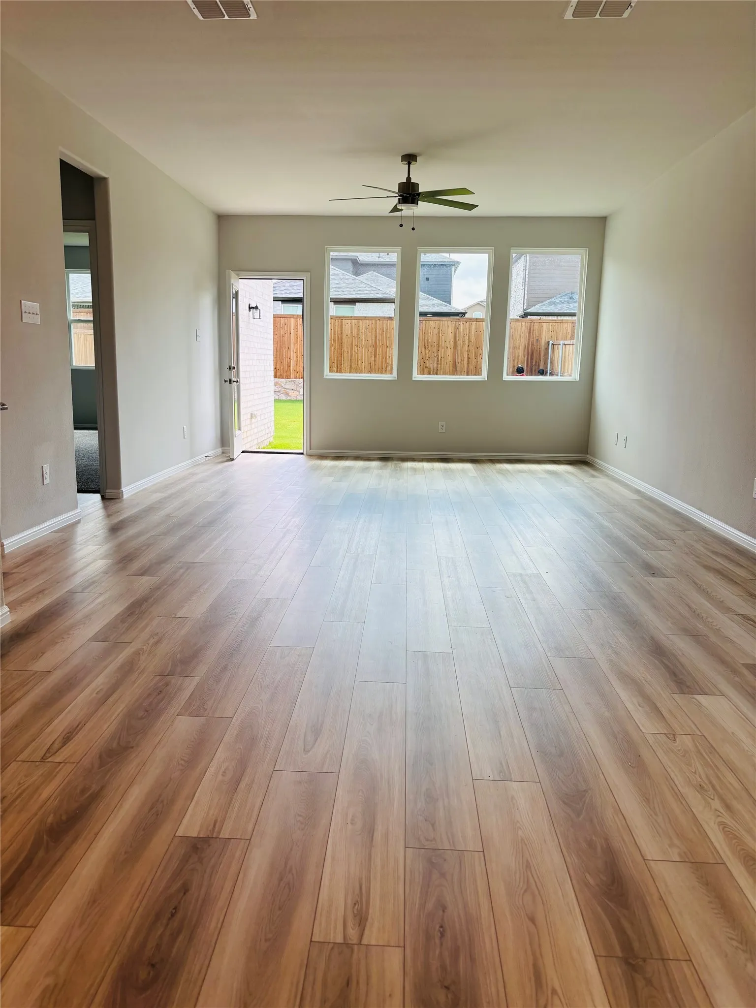 Unfurnished living room featuring a ceiling fan, plenty of natural light, and wood finished floors