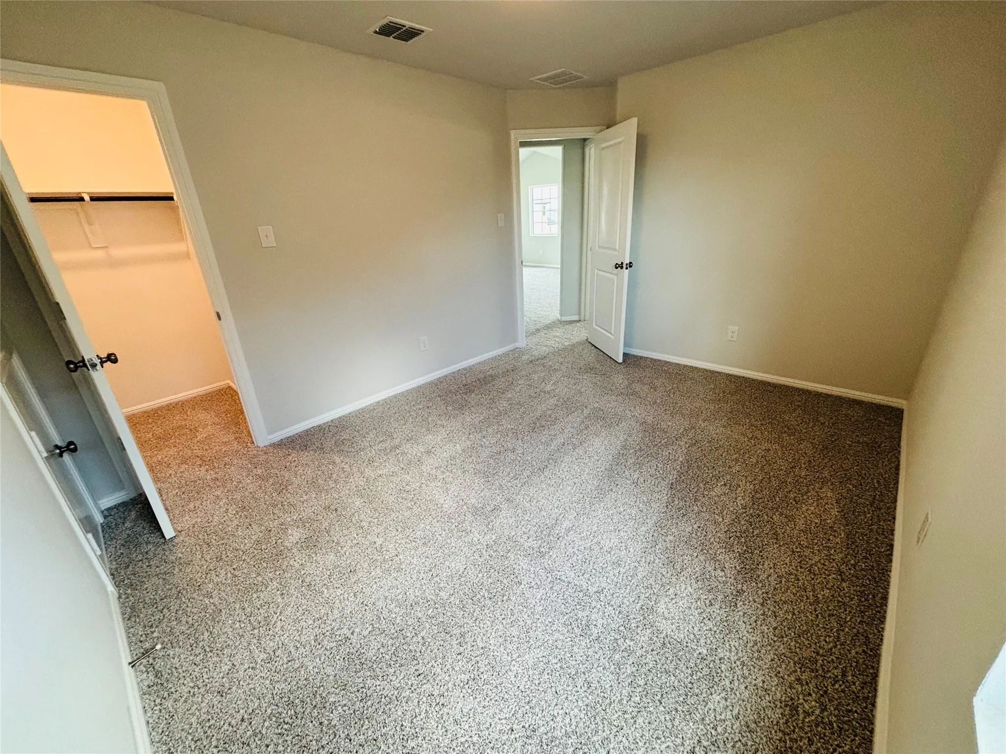 Unfurnished bedroom featuring a walk in closet, carpet, and a closet