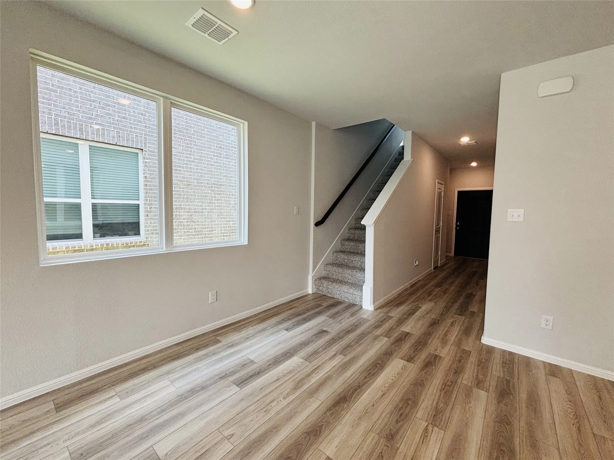 Unfurnished living room with light wood-style flooring, stairs, and recessed lighting