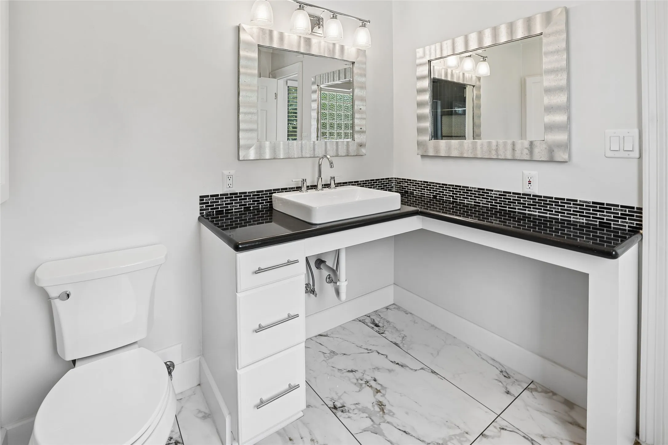 Bathroom featuring a rectangular vessel sink, black countertop, and black mosaic tile backsplash