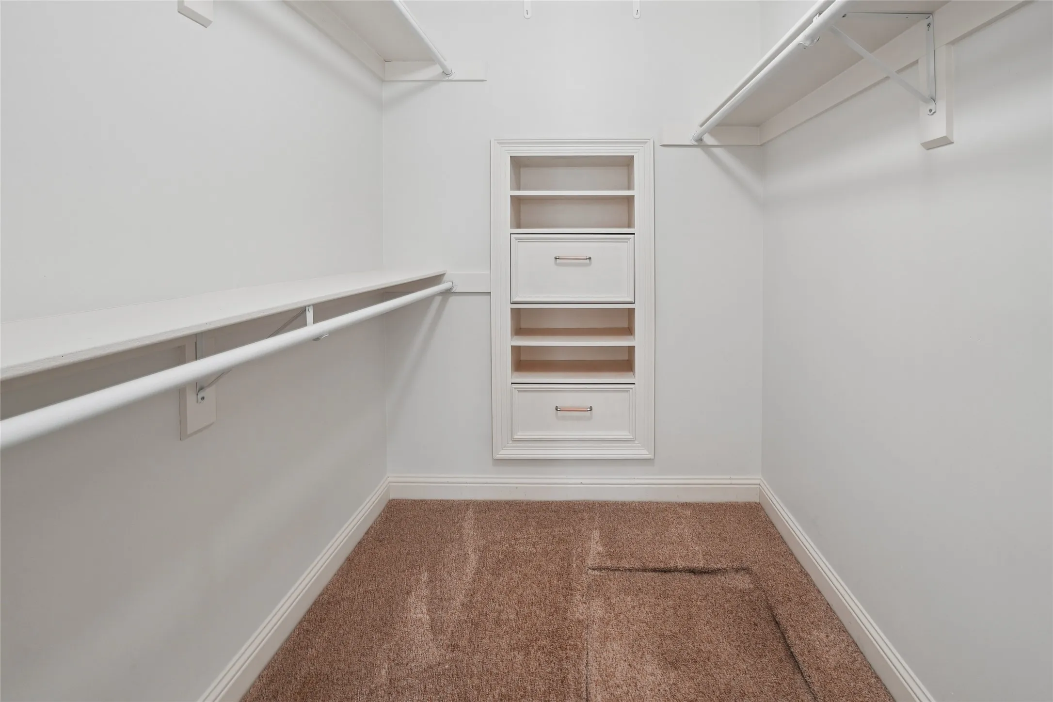 Walk-in closet featuring built-in shelving, hanging rods, and integrated drawers