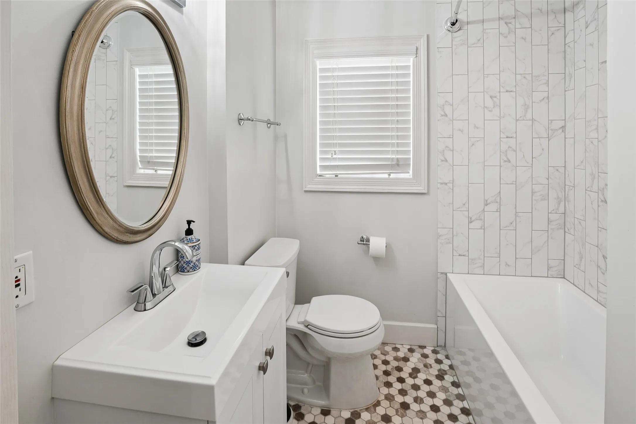 Bathroom featuring a white vanity with integrated sink, chrome faucet, and an oval framed mirror