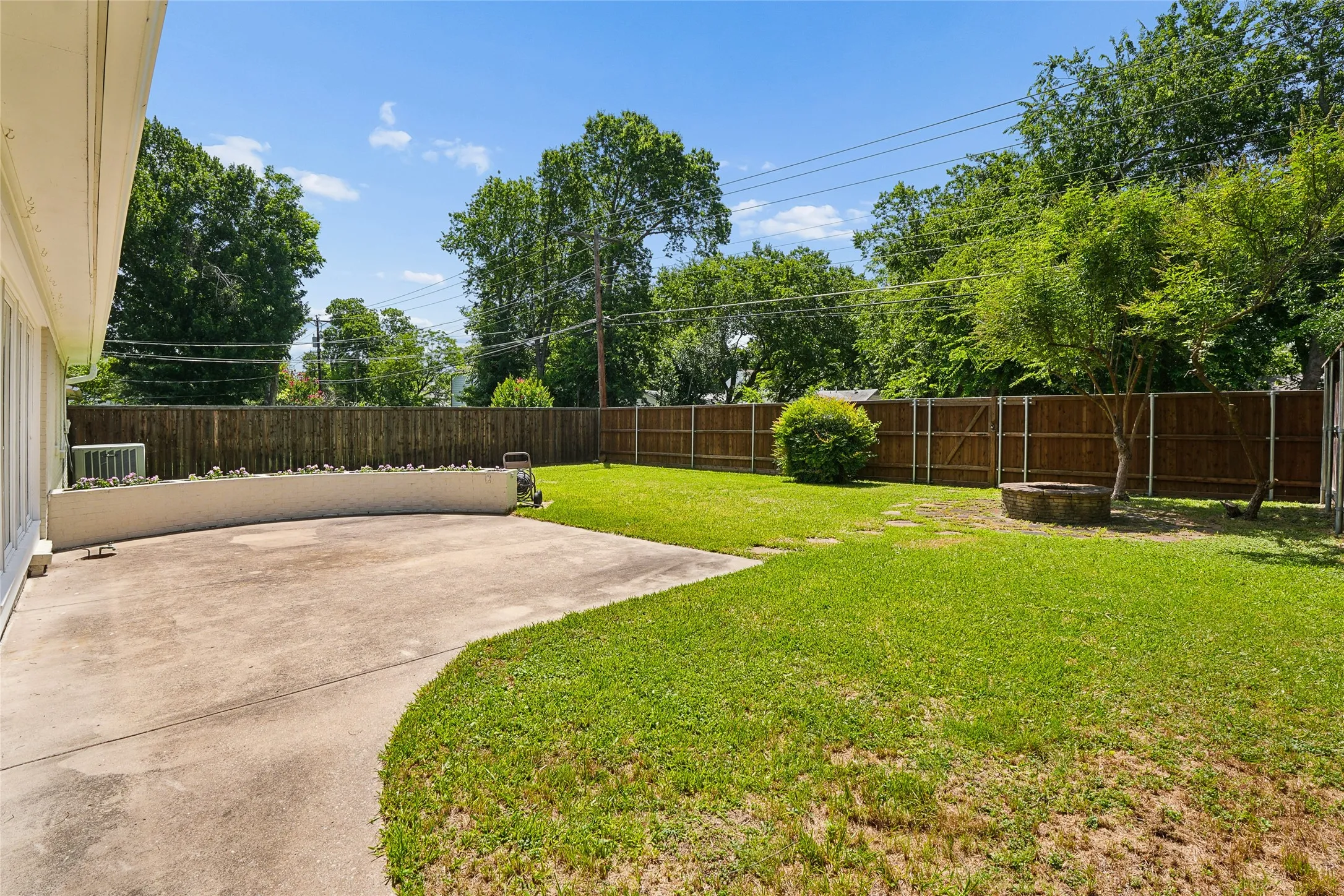 Spacious backyard featuring a concrete patio, curved planter box, and a solid wood privacy fence