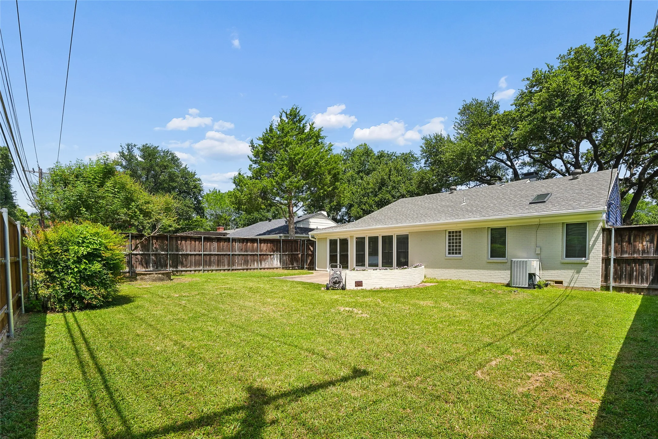 Expansive backyard featuring a manicured lawn, established privacy fencing, and mature perimeter trees