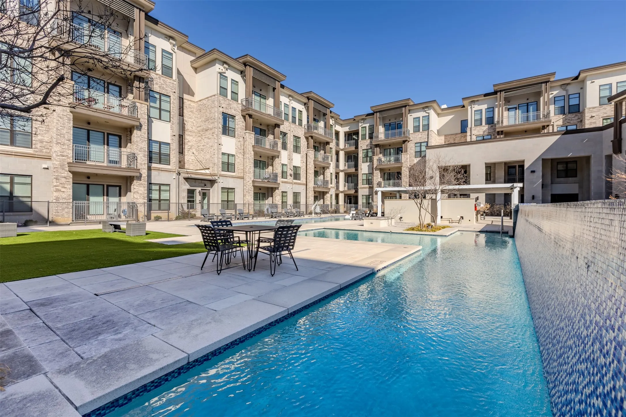 Expansive courtyard featuring a geometric pool, surrounding patio, and artificial turf lawn