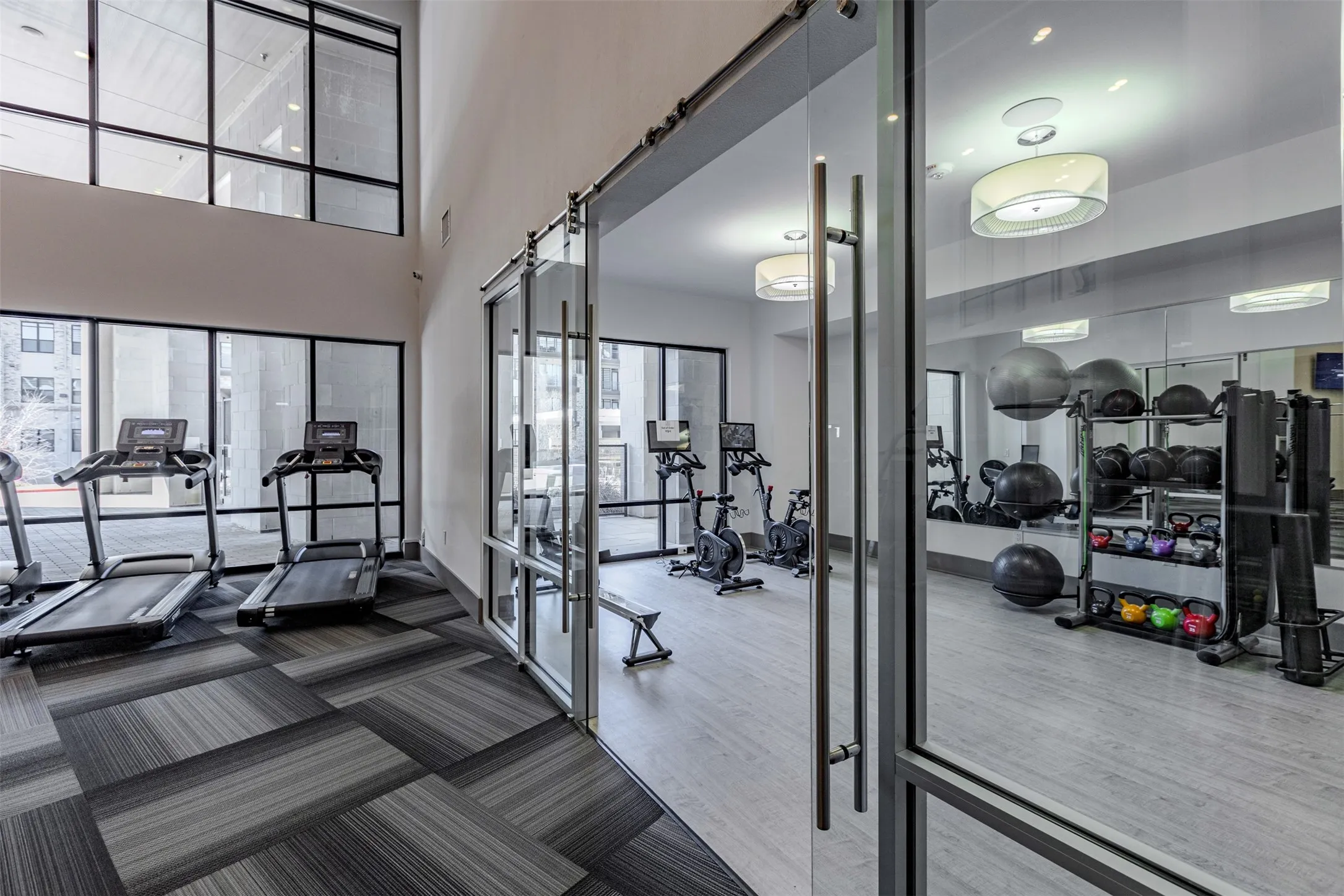 Fitness center featuring high ceilings, extensive windows, patterned carpet flooring, and a mirrored wall
