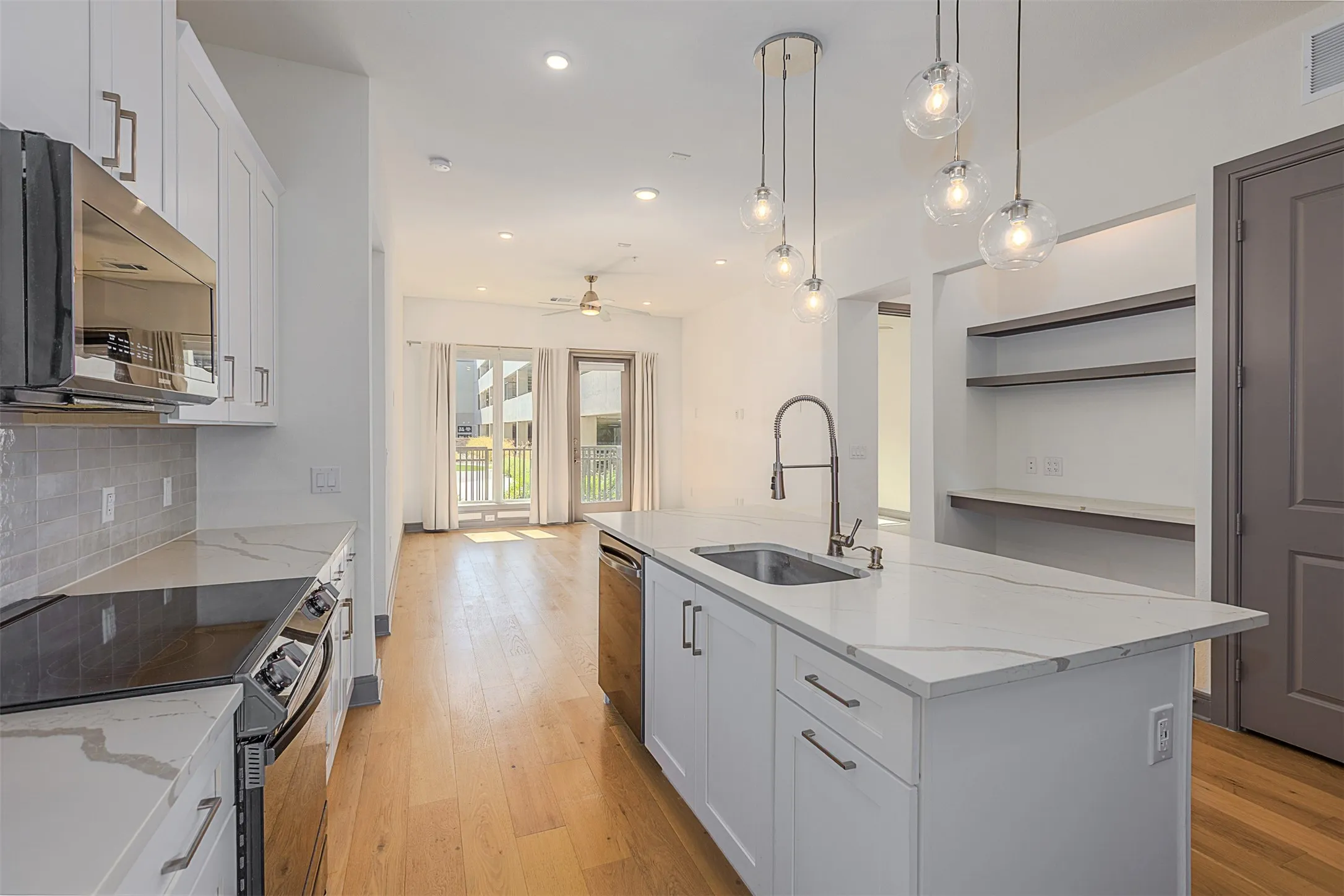 Modern kitchen island featuring a waterfall-edge countertop, undermount sink, and contemporary pendant lighting