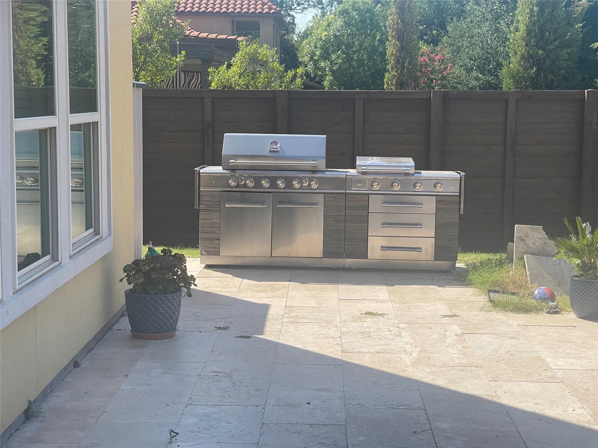 Outdoor kitchen featuring a built-in stainless steel grill, integrated storage, and a stone-look base