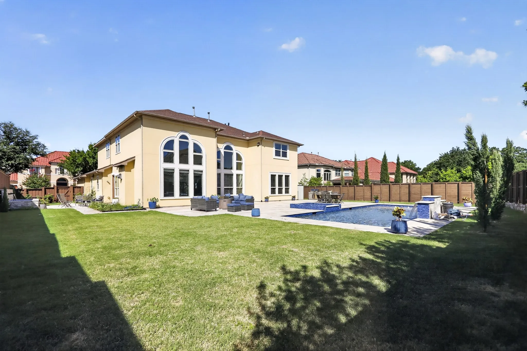 Expansive backyard featuring a rectangular swimming pool with integrated spa and waterfall features