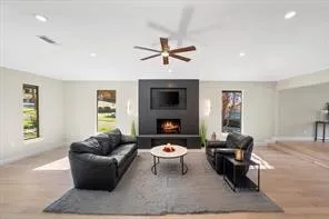 Spacious living area featuring a modern fireplace with integrated media console, wood-finish flooring, recessed lighting, and a ceiling fan