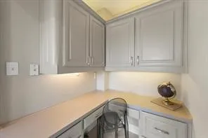 Integrated corner desk with light grey cabinetry, ample countertop space, and under-cabinet lighting