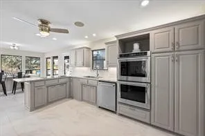 Kitchen featuring light gray shaker cabinetry, stainless steel double wall ovens, a coordinating dishwasher, recessed lighting, and a ceiling fan
