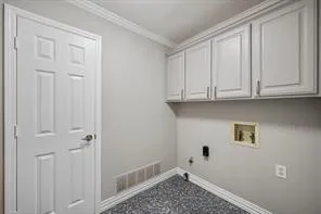 Utility area featuring white shaker-style cabinetry, crown molding, and a patterned tile floor