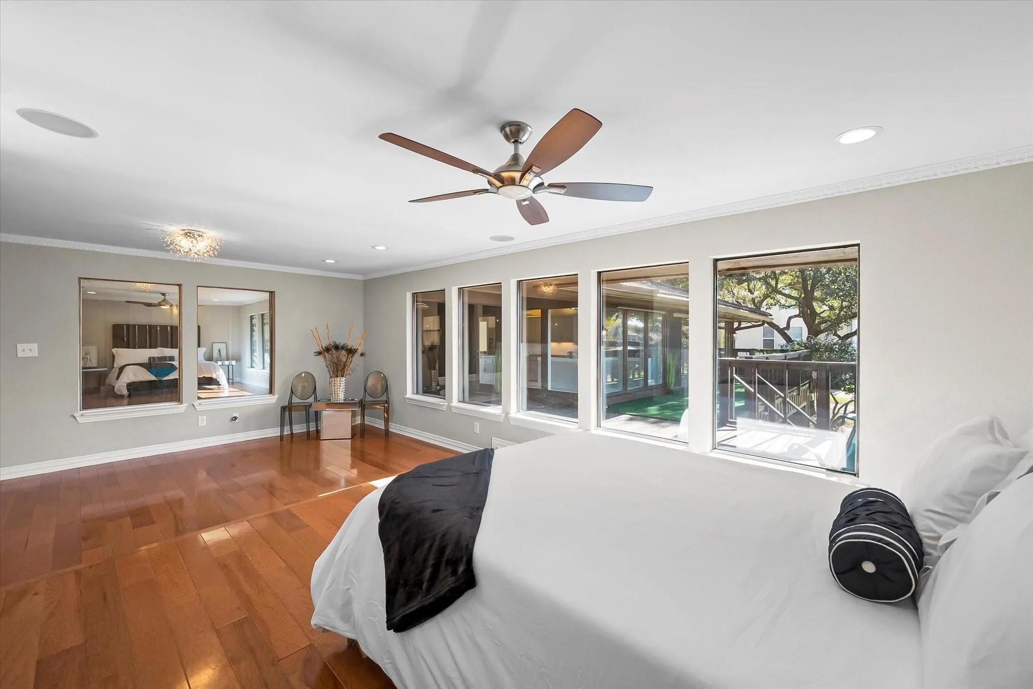 Hardwood flooring throughout, featuring a ceiling fan with integrated lighting, recessed lighting, and multiple windows