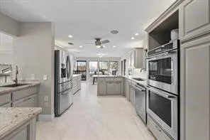 Kitchen featuring a double wall oven, stainless steel appliances, light cabinetry, recessed lighting, and light-toned flooring