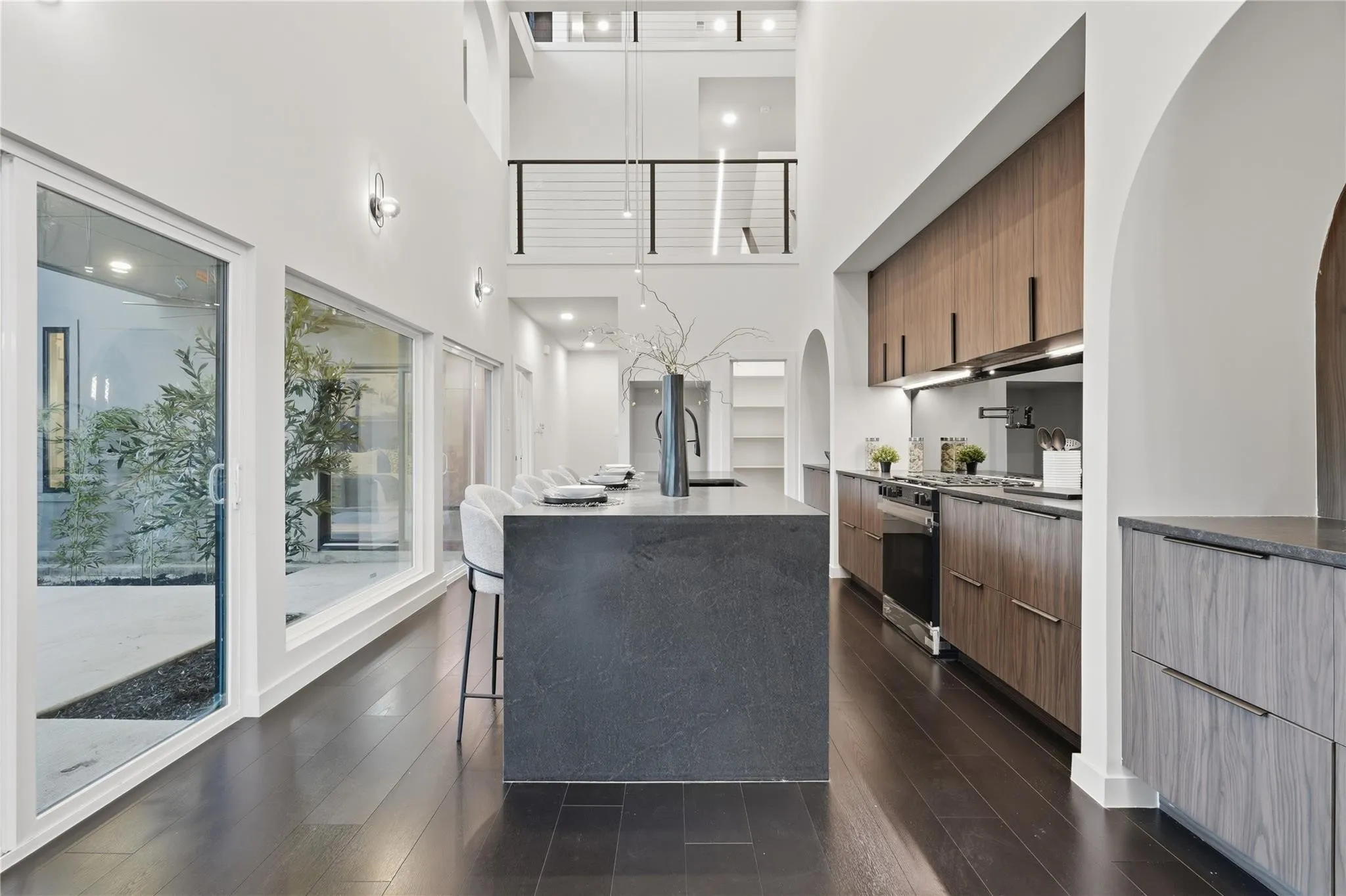 Modern kitchen with dark wood-finish flooring, a waterfall island, and integrated stainless steel appliances