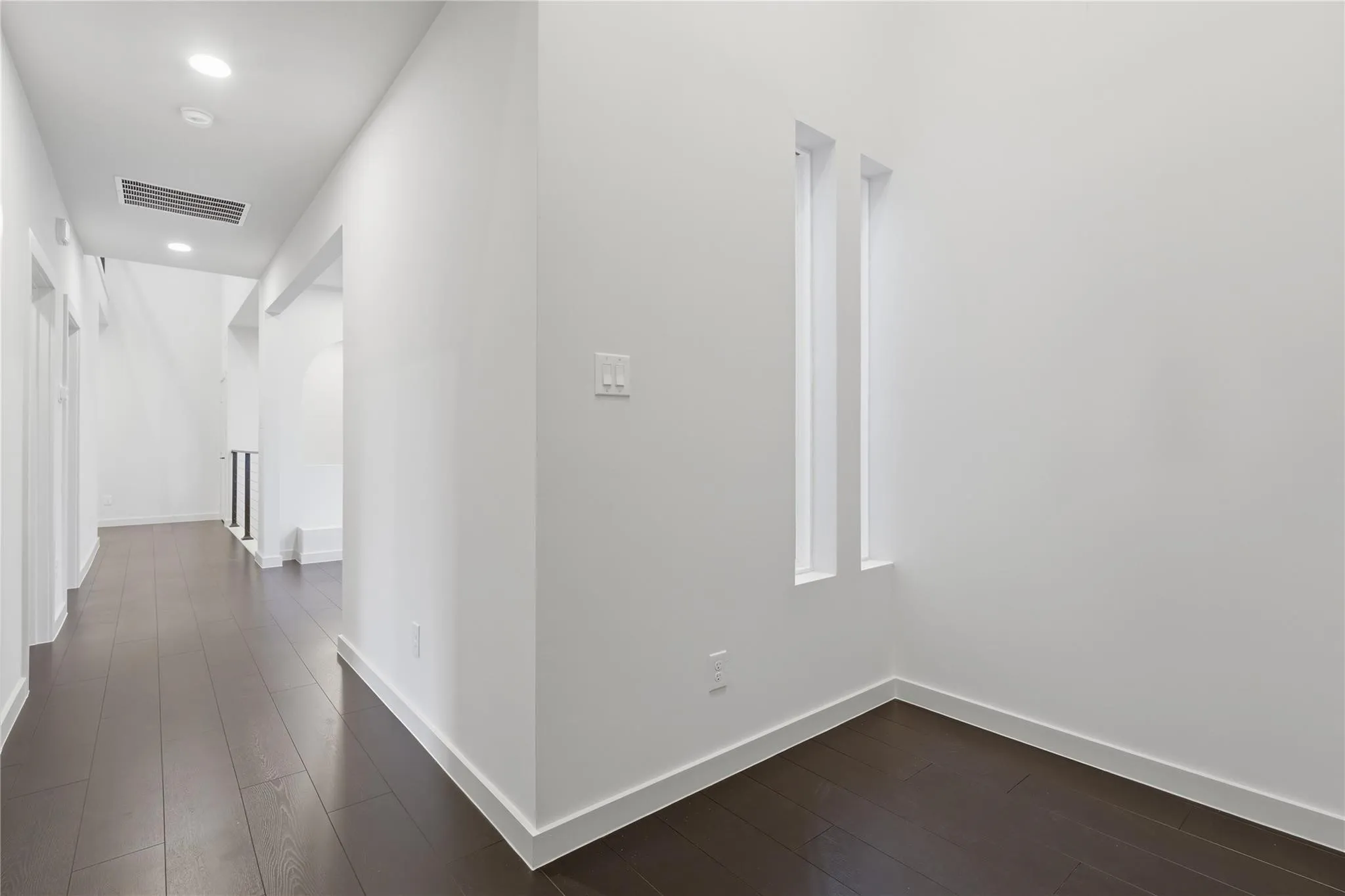 Hallway featuring dark wood-finish flooring, recessed lighting, and white baseboards