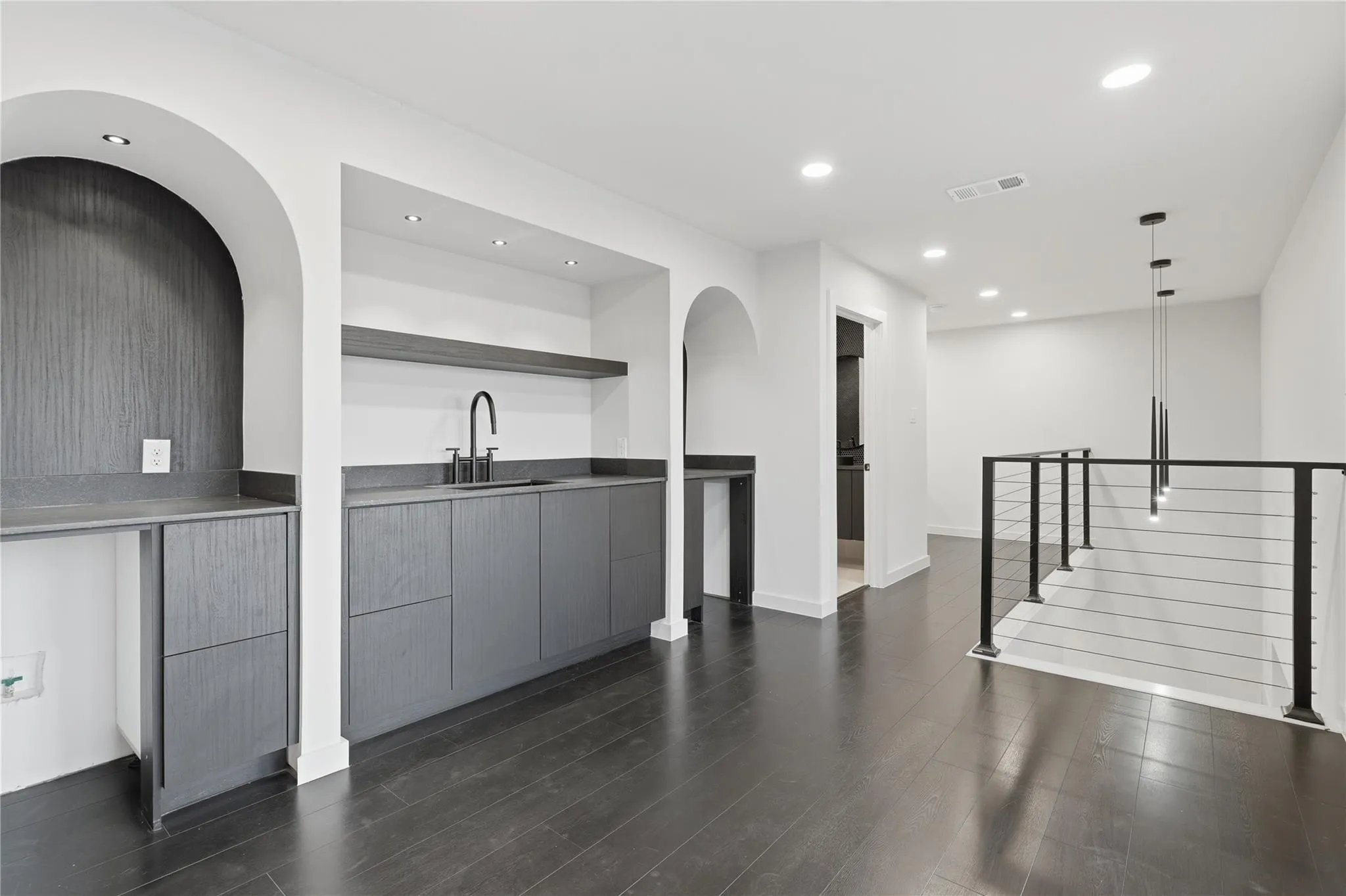 Second-story landing featuring a wet bar with dark cabinetry, integrated sink, and matte black faucet
