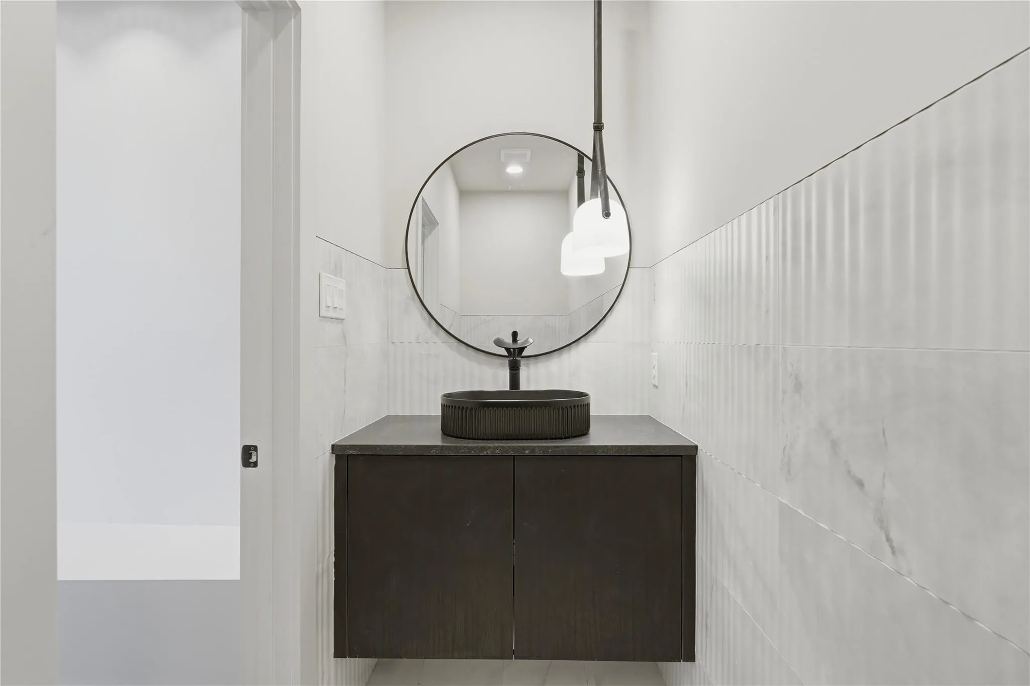 Floating vanity with a dark wood-finish cabinet and a charcoal vessel sink