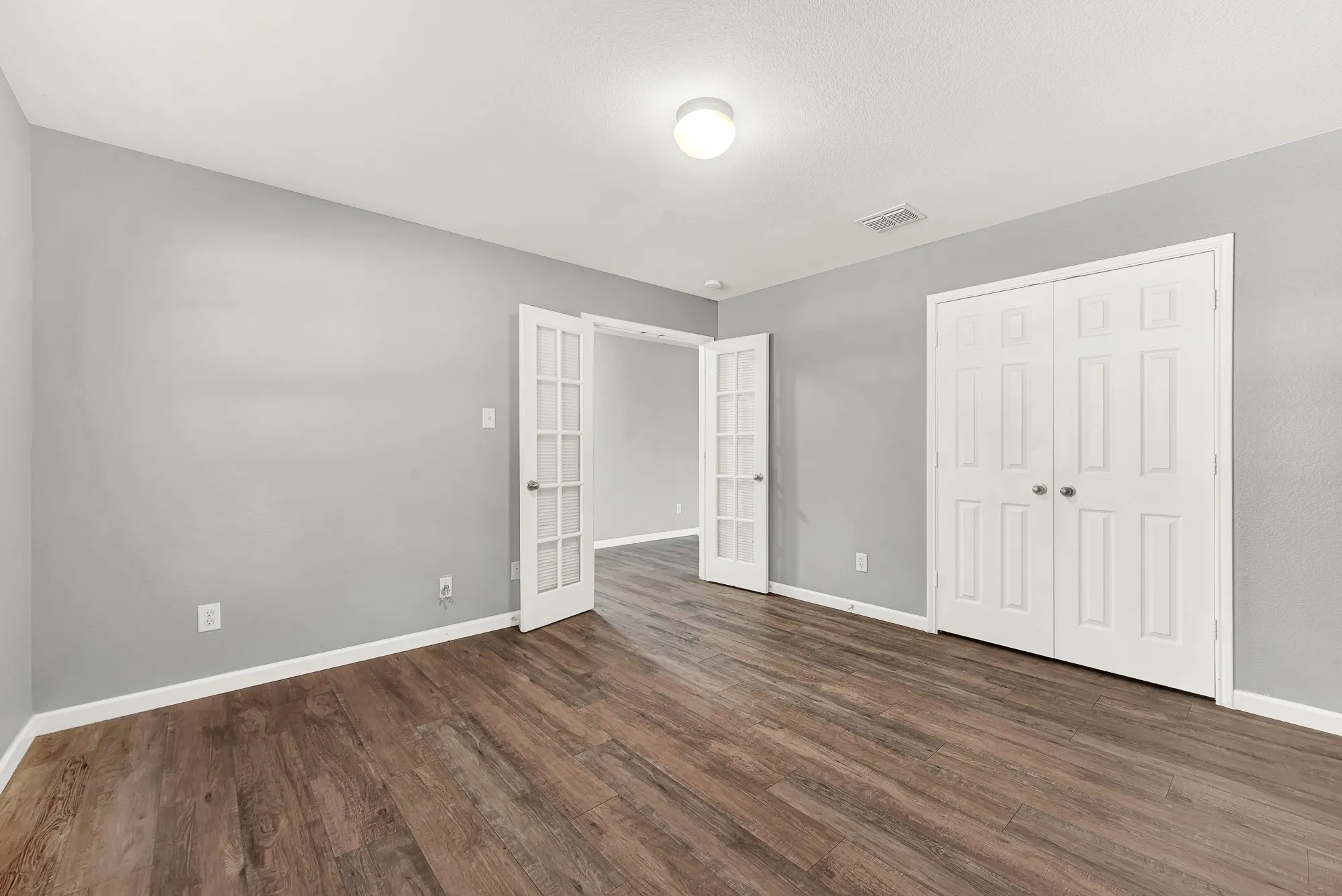 Room featuring wood-finish flooring, light grey walls, and white baseboards