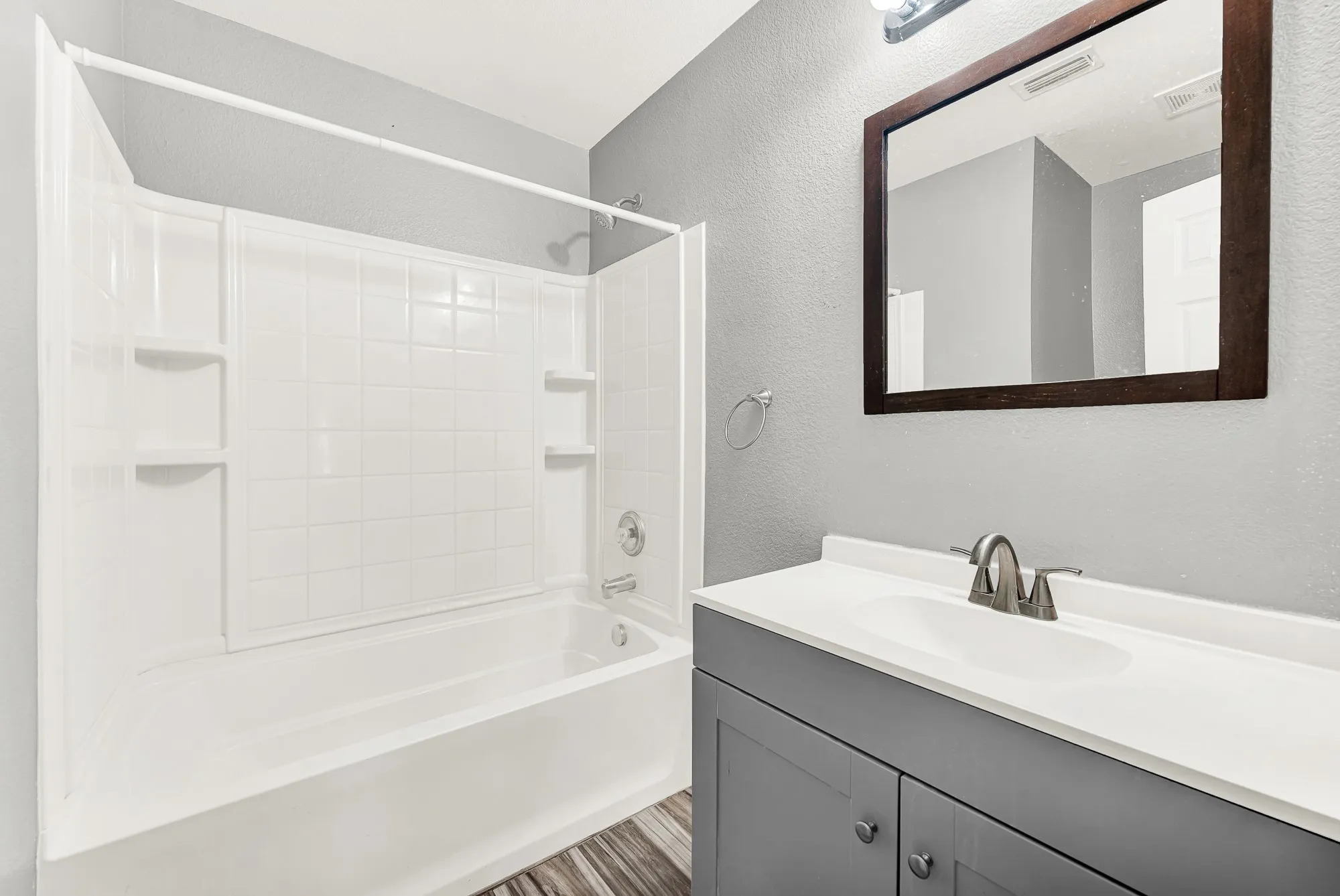 Bathroom featuring a white tub and shower surround with integrated shelving