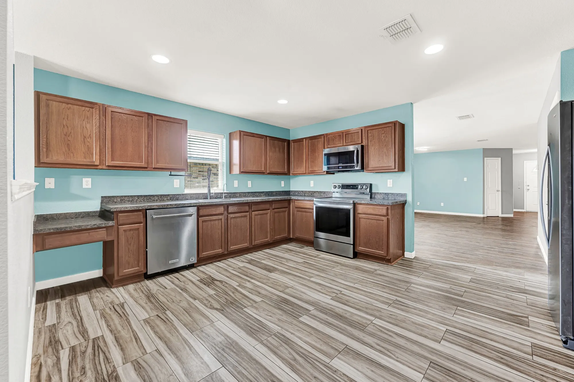 U-shaped kitchen featuring wood-finish cabinetry, dark countertops, and stainless steel appliances
