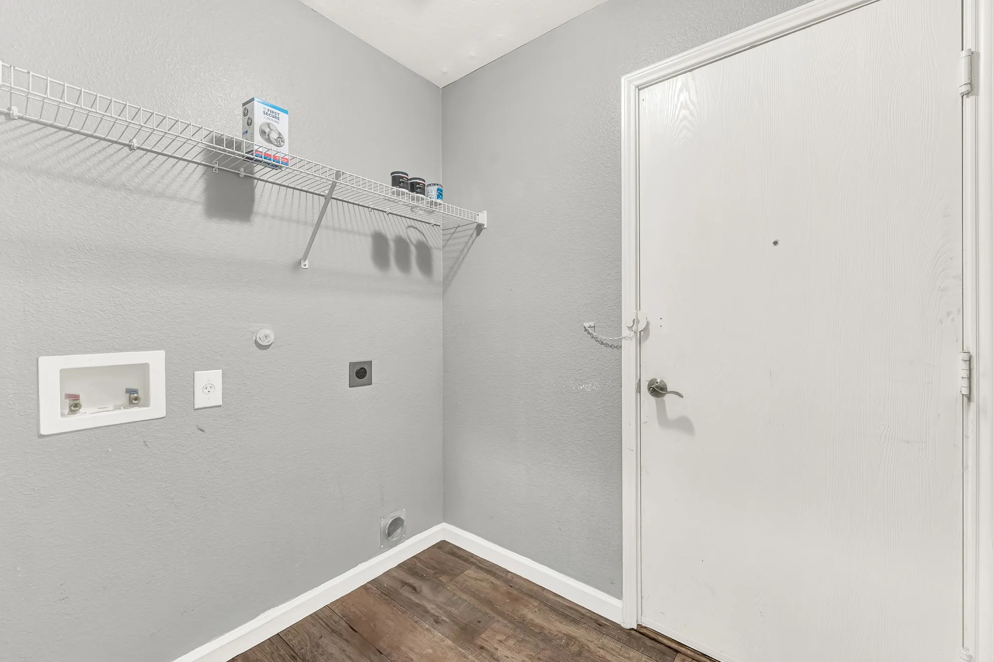 Utility room featuring wood-finish flooring, light gray wall paint, and white baseboards