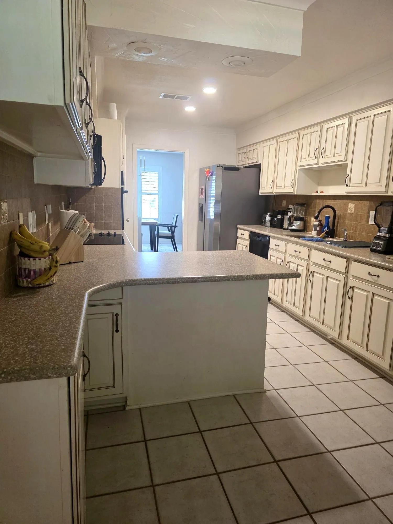 Kitchen featuring extensive cabinetry with decorative paneling, a large range hood, and a built-in window opening