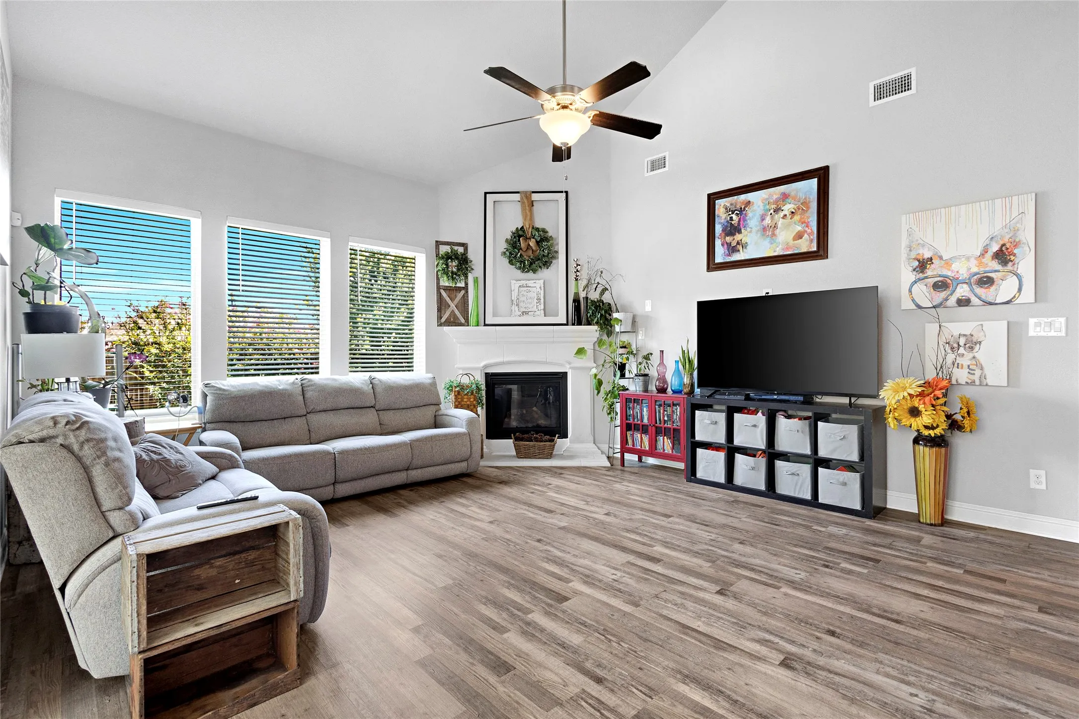 Spacious living room featuring wood-finish flooring, vaulted ceilings, and a ceiling fan