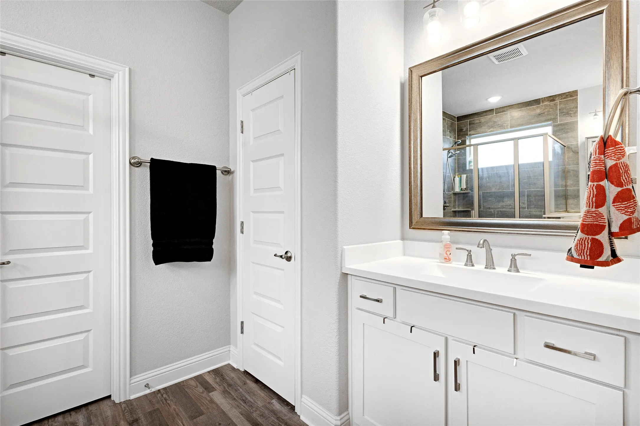 Bathroom vanity featuring a white countertop with an integrated sink, brushed nickel faucet, and white cabinetry with brushed nickel hardware