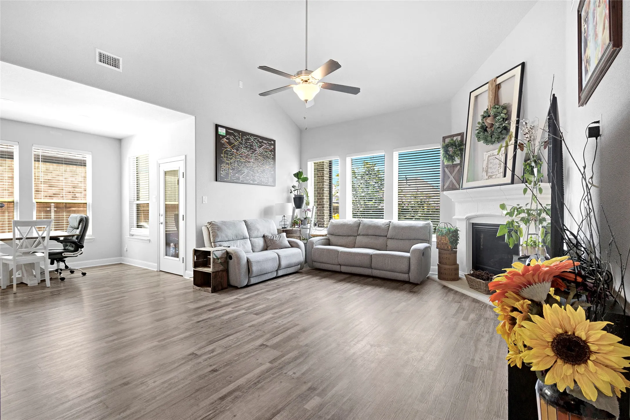 Spacious living area featuring wood-finish flooring, a vaulted ceiling, and a ceiling fan with integrated lighting