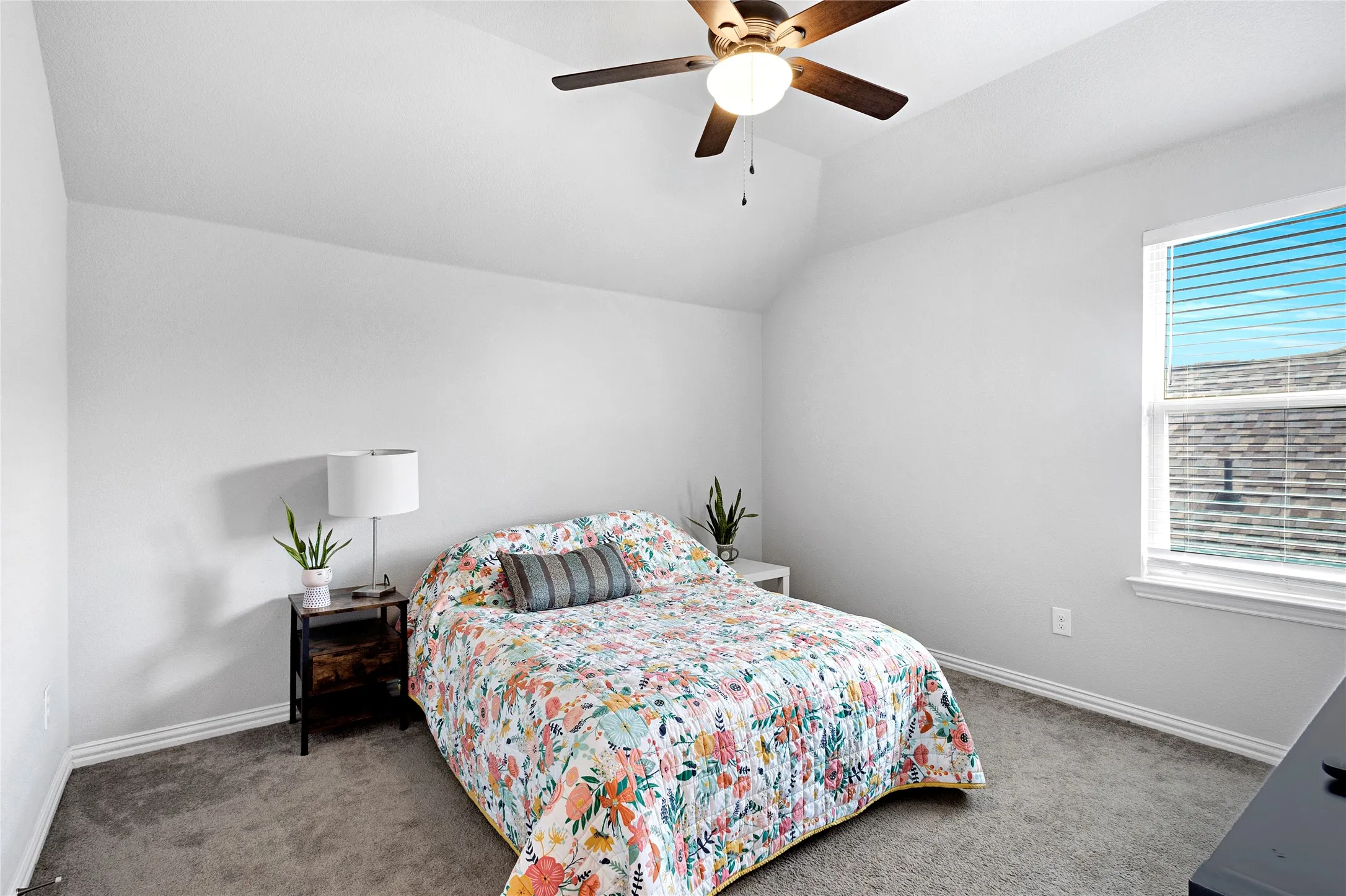 Carpeted bedroom featuring a vaulted ceiling with a ceiling fan, a window with blinds, and white walls