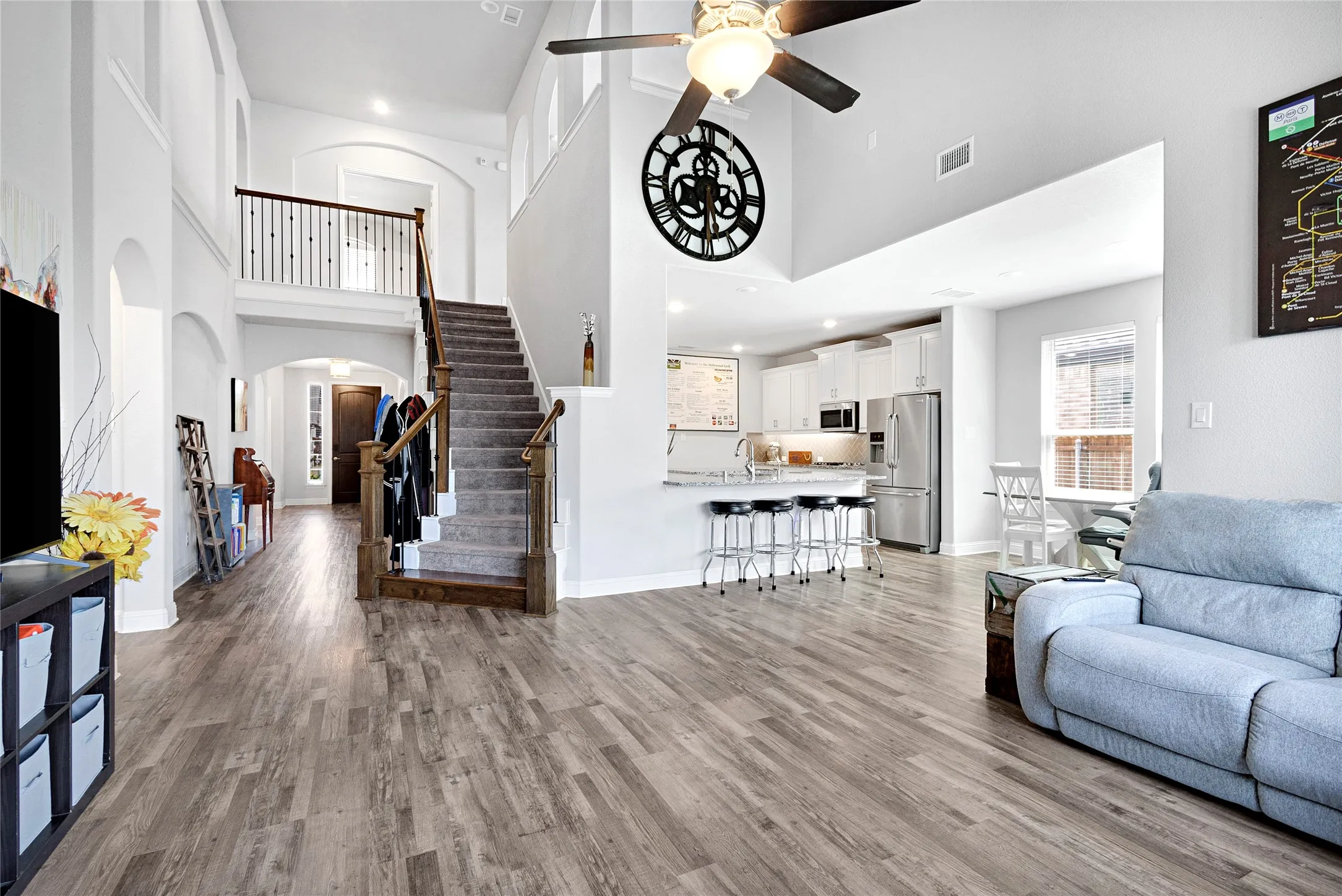 Open concept interior featuring wood-finish flooring, a two-story ceiling, and a prominent staircase with wood newel posts and a carpeted tread