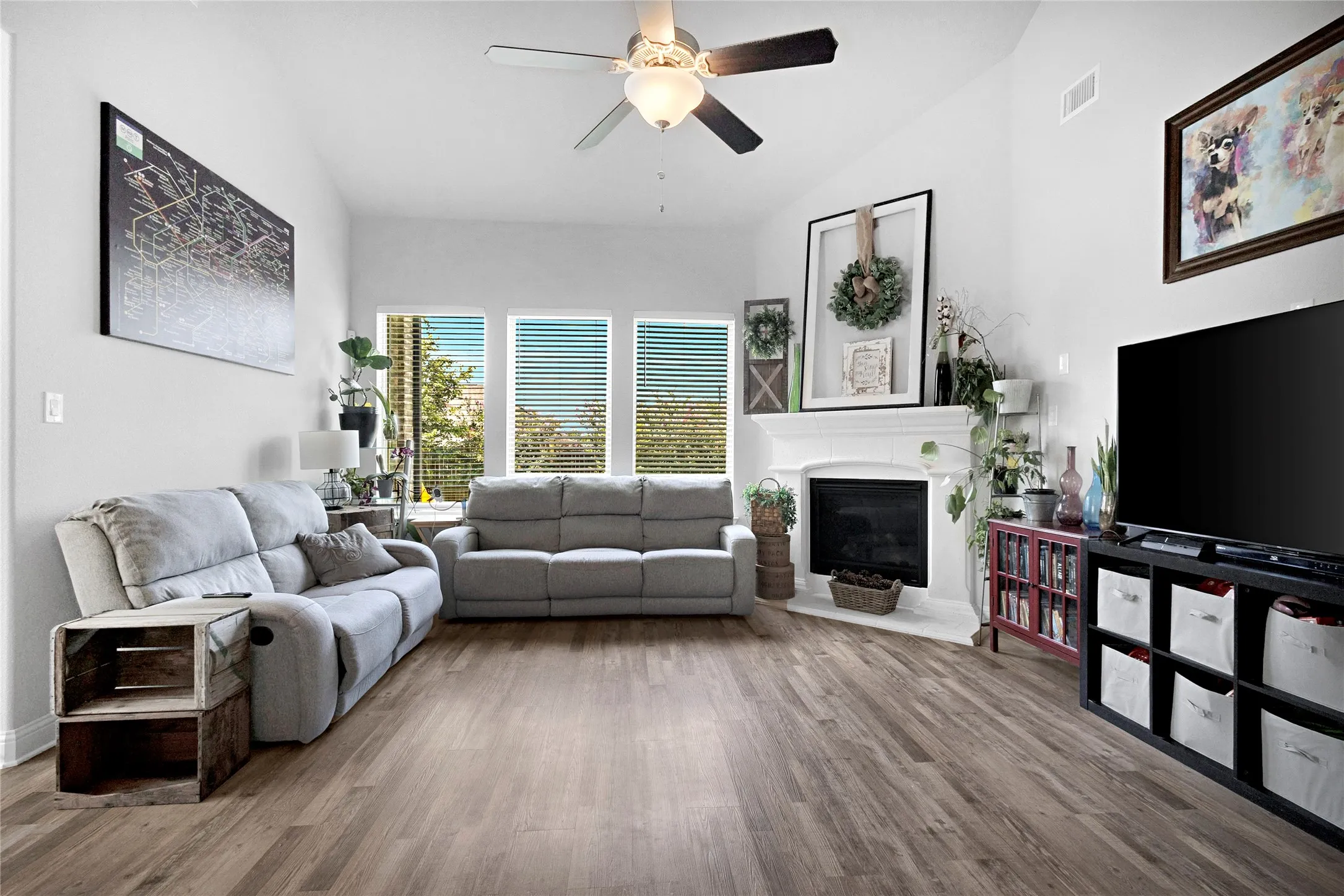 Spacious living area featuring wood-finish flooring, a white mantel fireplace, and a vaulted ceiling