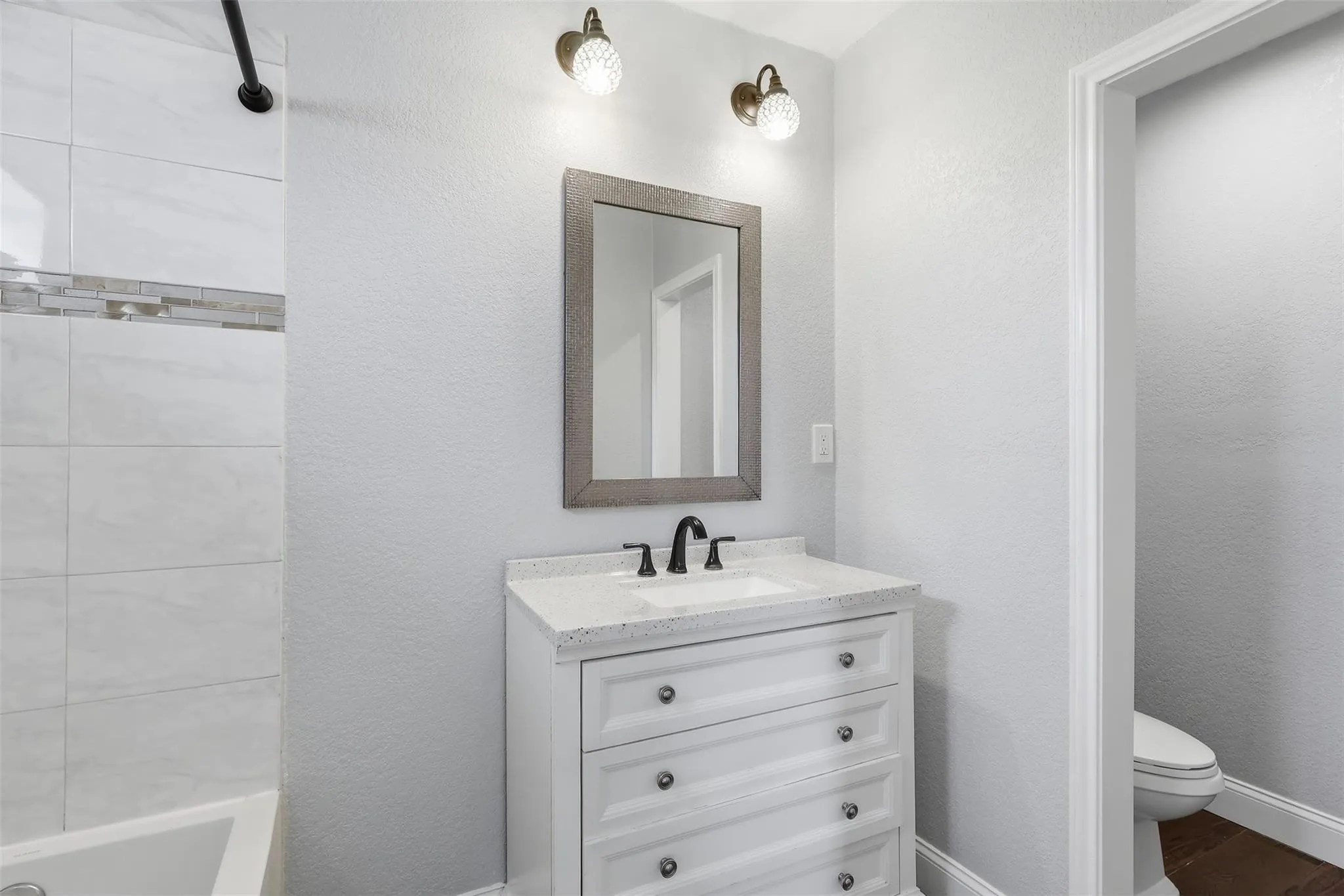Bathroom vanity with a white countertop and integrated sink, matte black faucet, and a framed mirror
