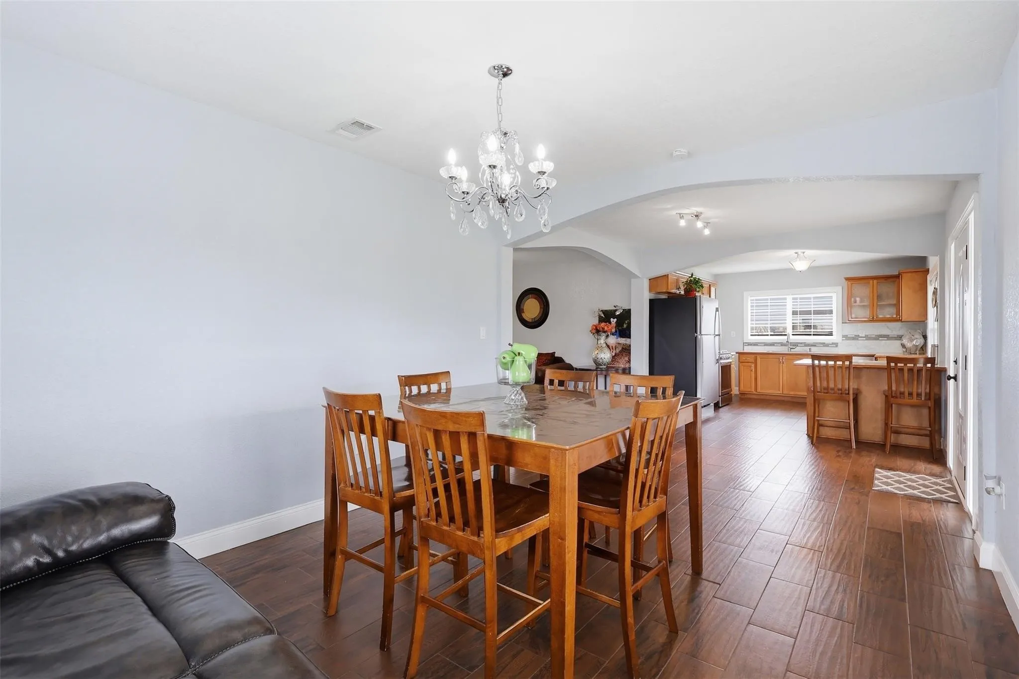 Open-concept dining area with wood-finish flooring, a contemporary chandelier, and arched doorways