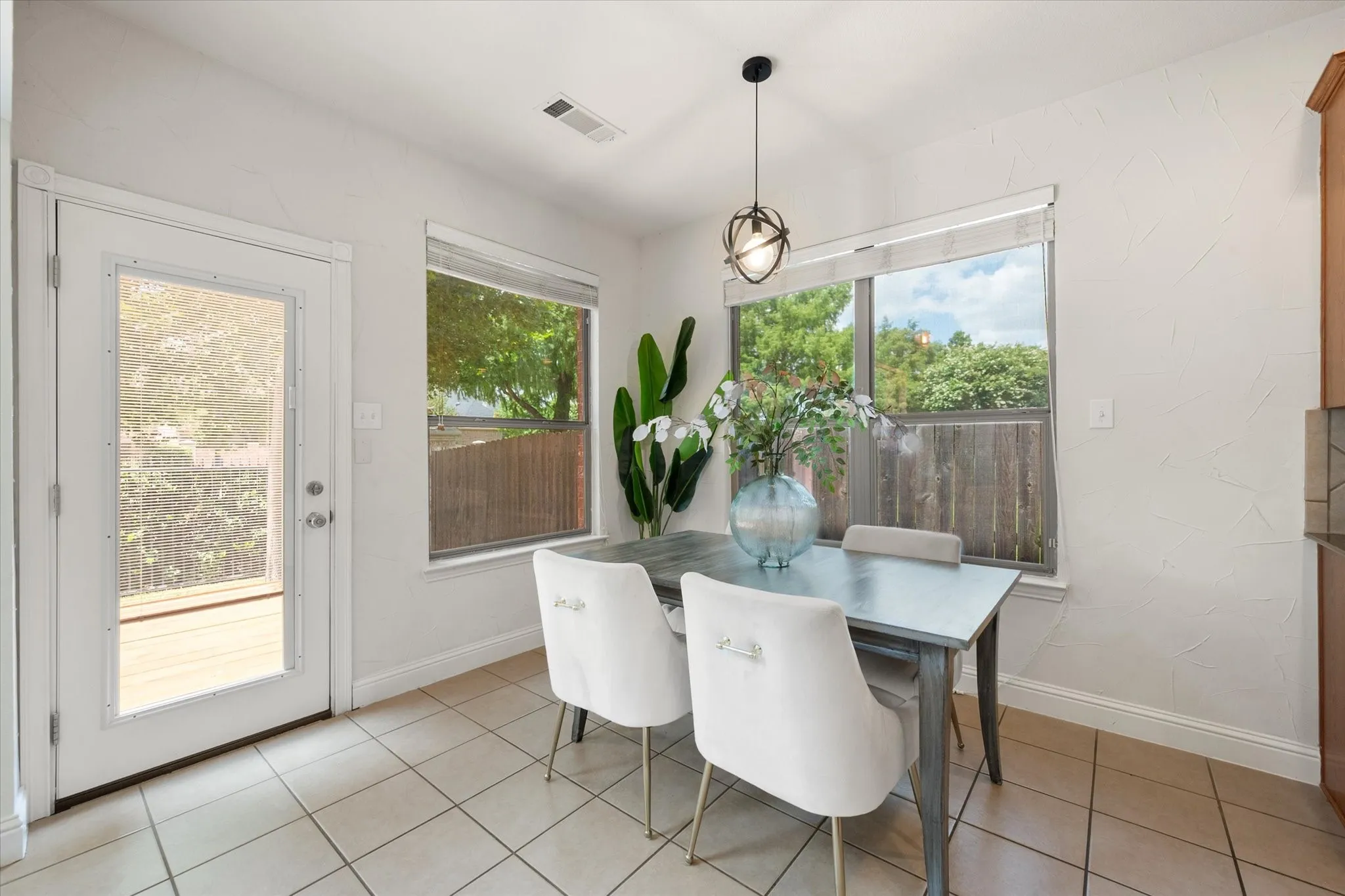 Dining area with tile flooring, a full-light exterior door, and two windows with blinds