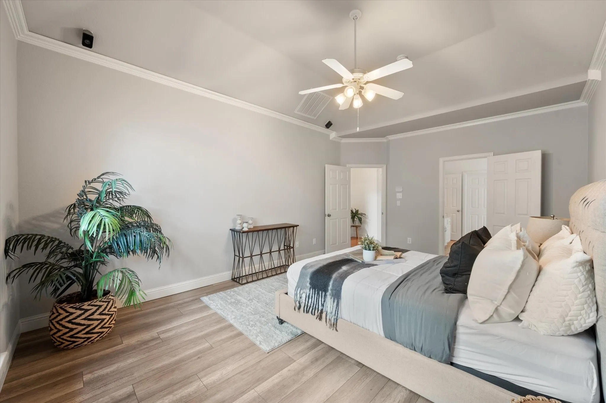 Downstairs Primary bedroom with vaulted ceiling with white crown molding and ceiling fan
