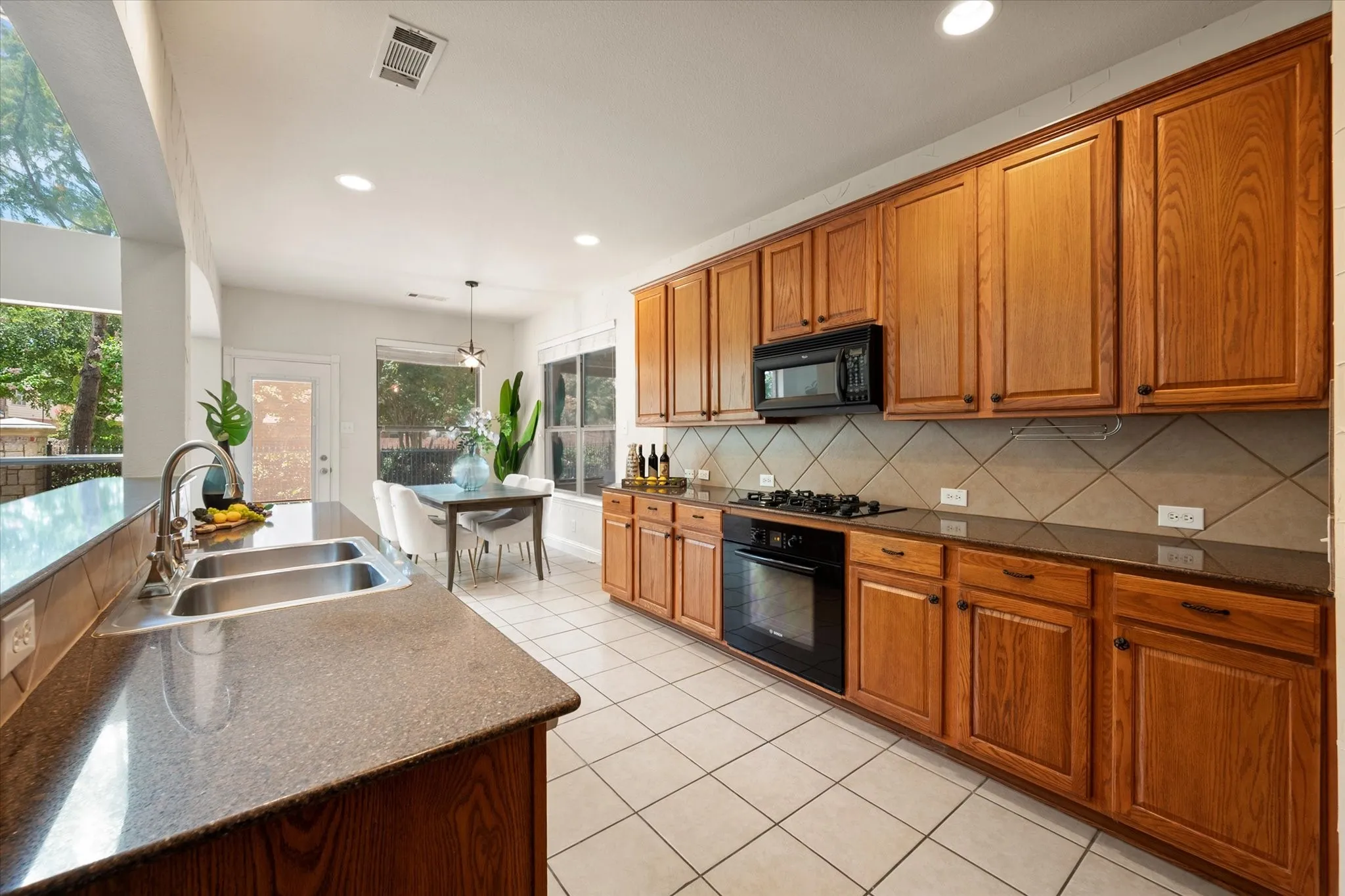 Kitchen featuring wood cabinetry, dark countertops, built-in microwave, integrated oven and cooktop, and tile flooring