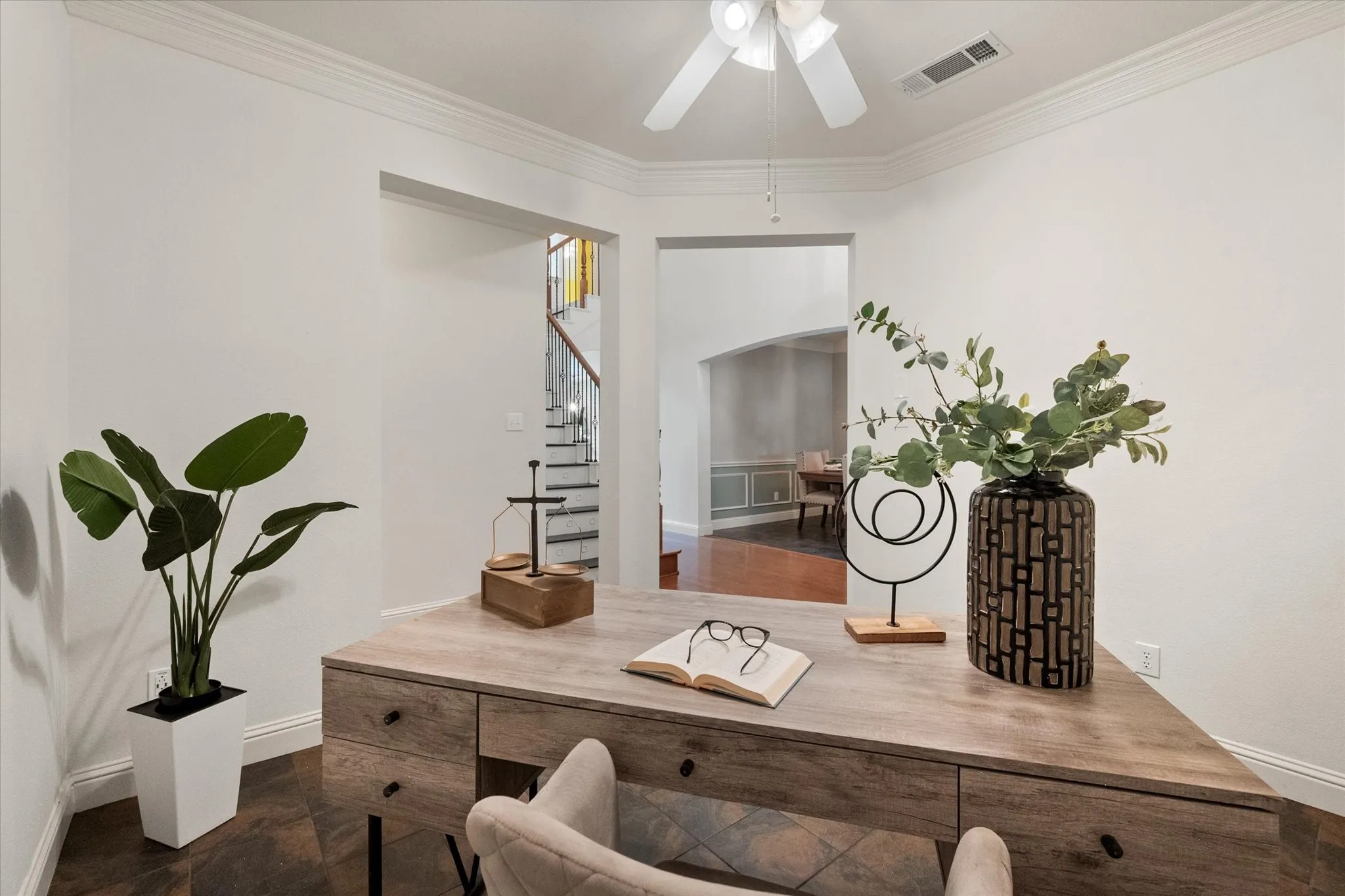 Flexible room with crown molding and a ceiling fan, featuring dark-toned flooring
