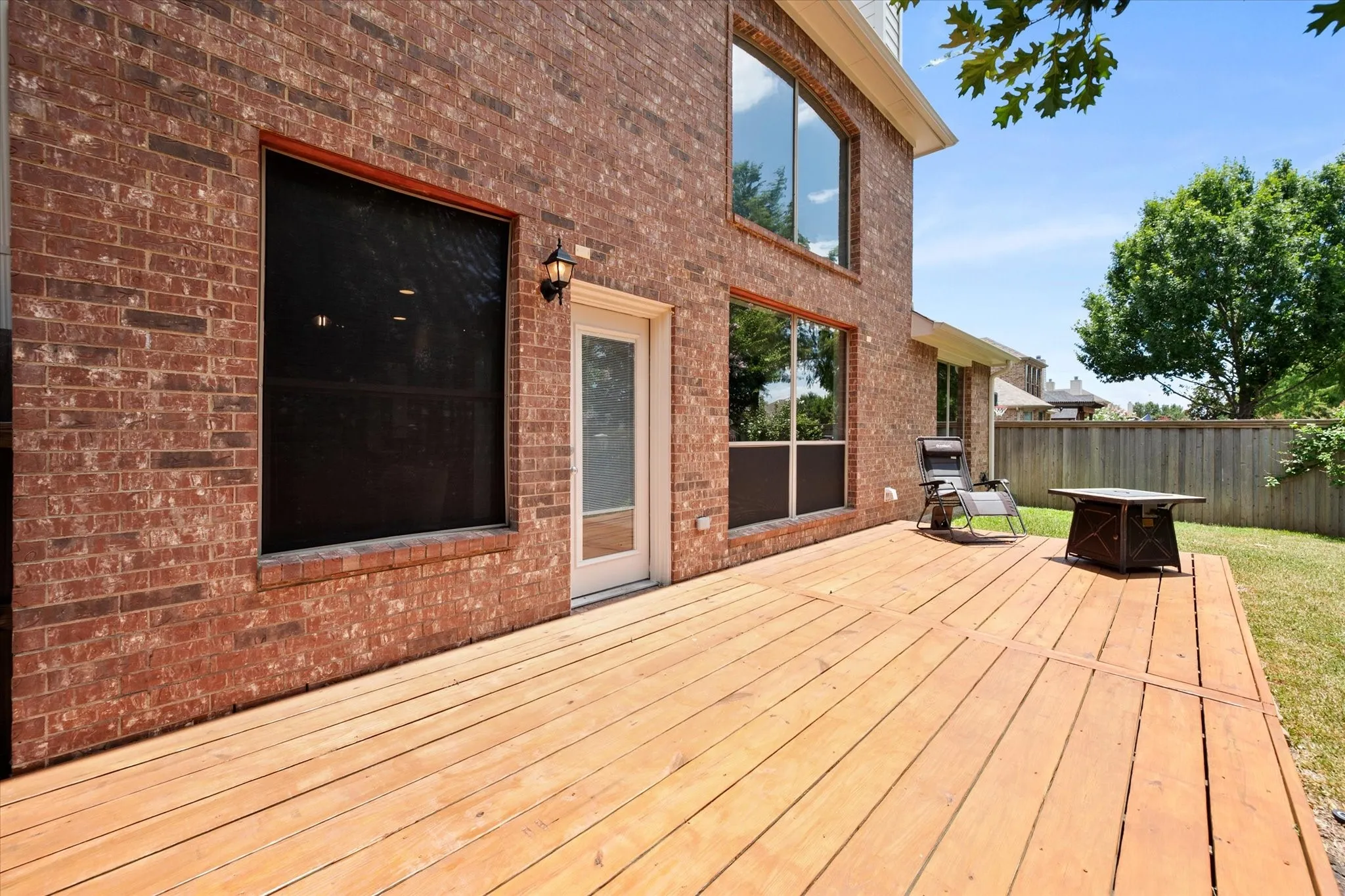Spacious wood deck with red brick exterior and multiple large windows