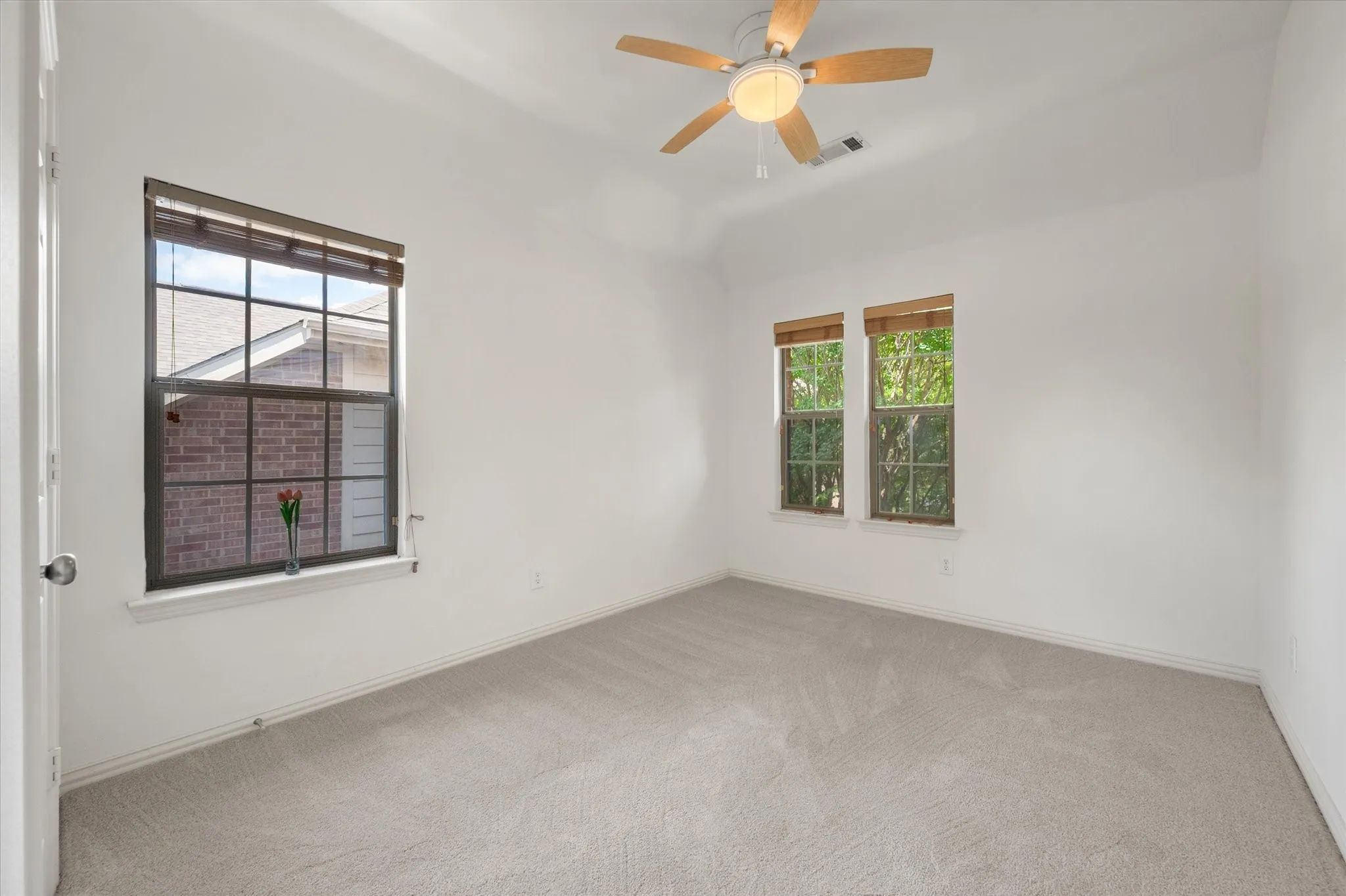 Spacious upstairs bedroom with vaulted ceiling and light-toned carpet flooring