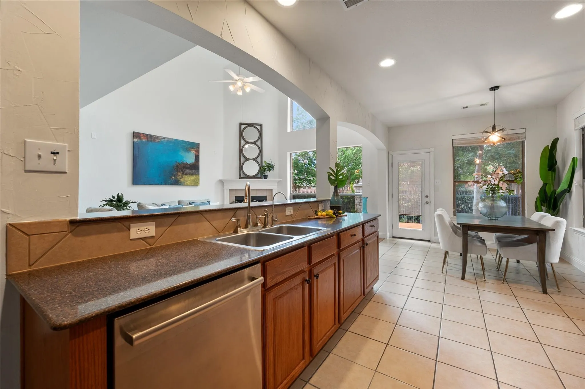 Kitchen featuring wood cabinetry, integrated double basin sink, stainless steel dishwasher, and stone countertops