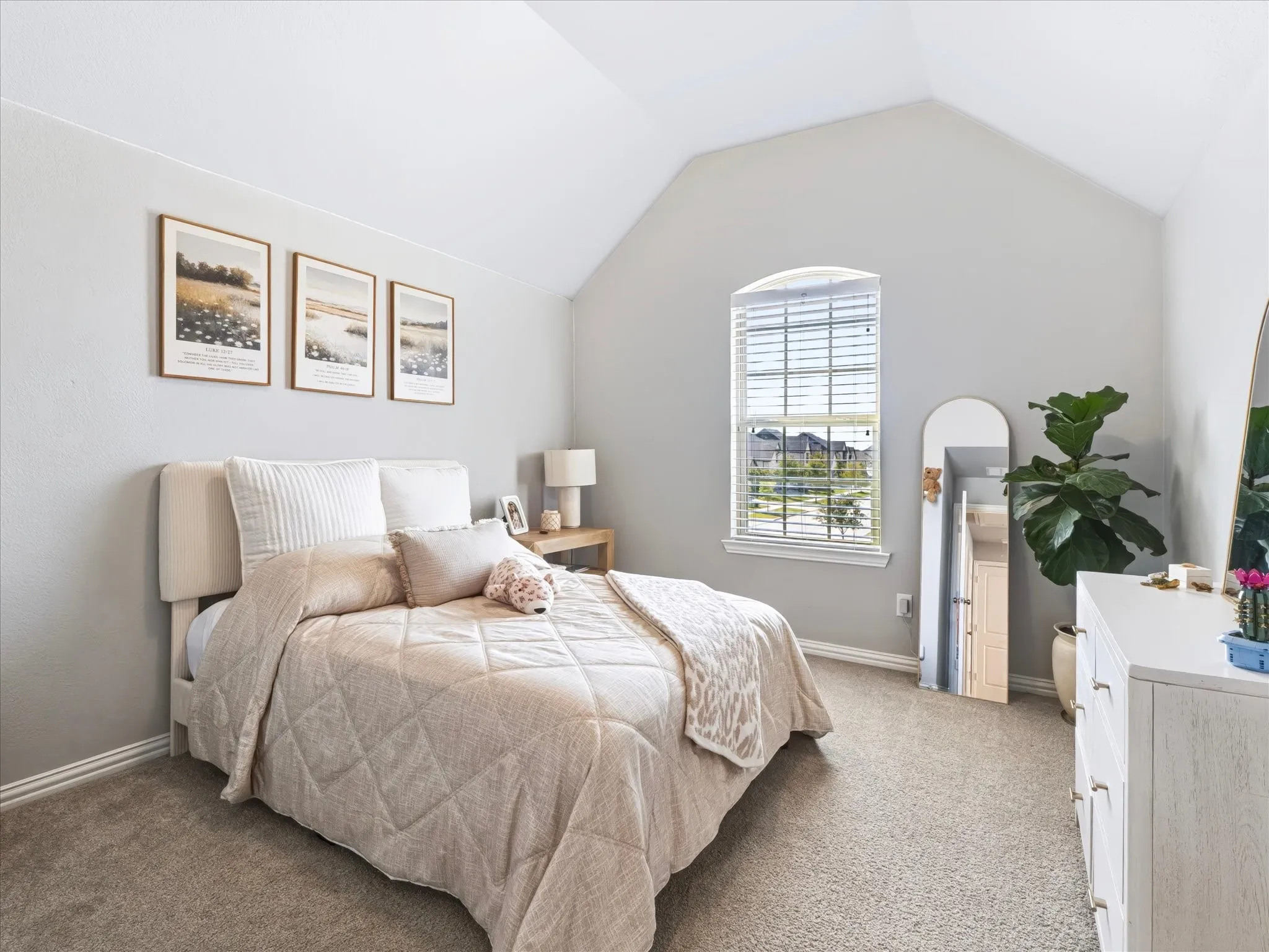 Vaulted ceiling with an arched window, soft gray wall paint, and plush carpeting