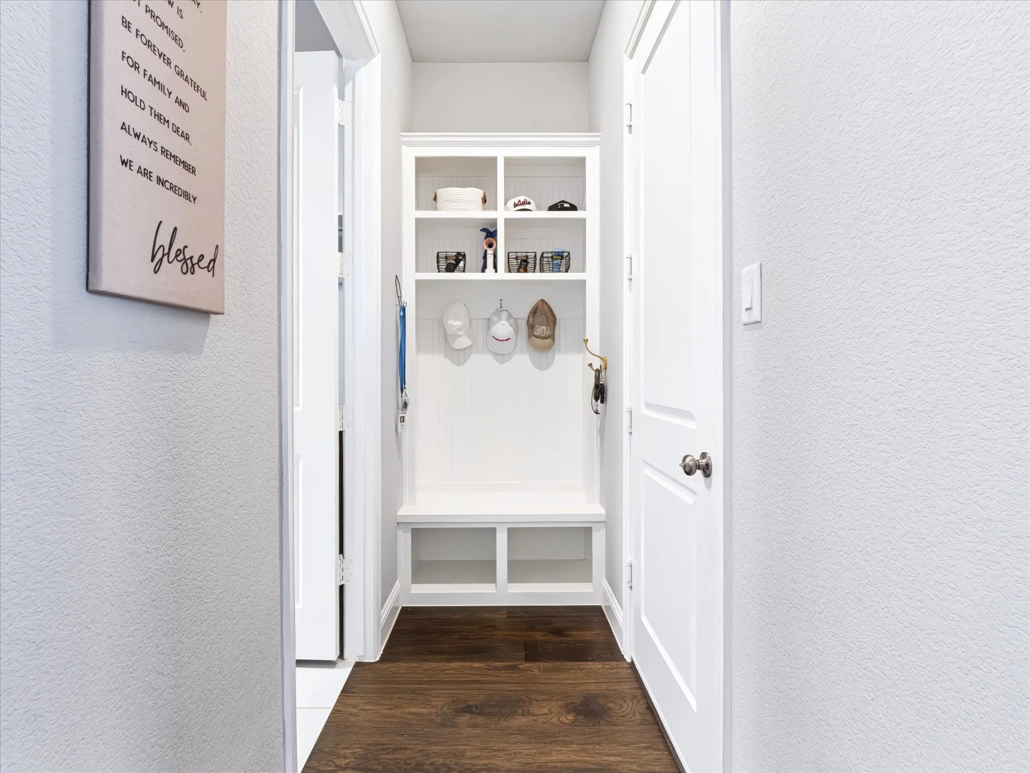 Built-in bench with cubby storage, upper shelving, and dark wood-finish flooring