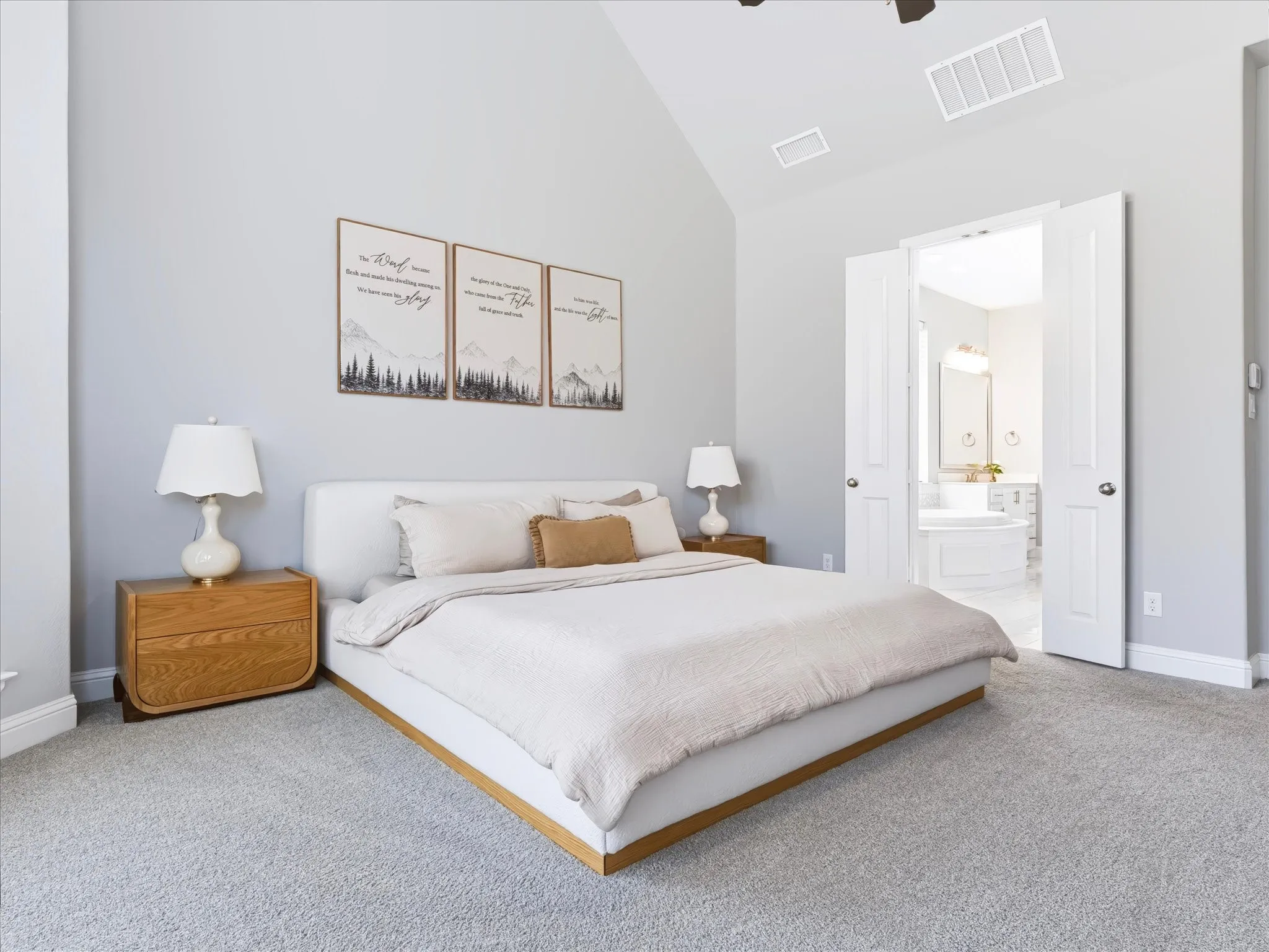 Vaulted ceiling with ceiling fan, light gray carpeting, and double-door entry to the bathroom featuring a built-in tub