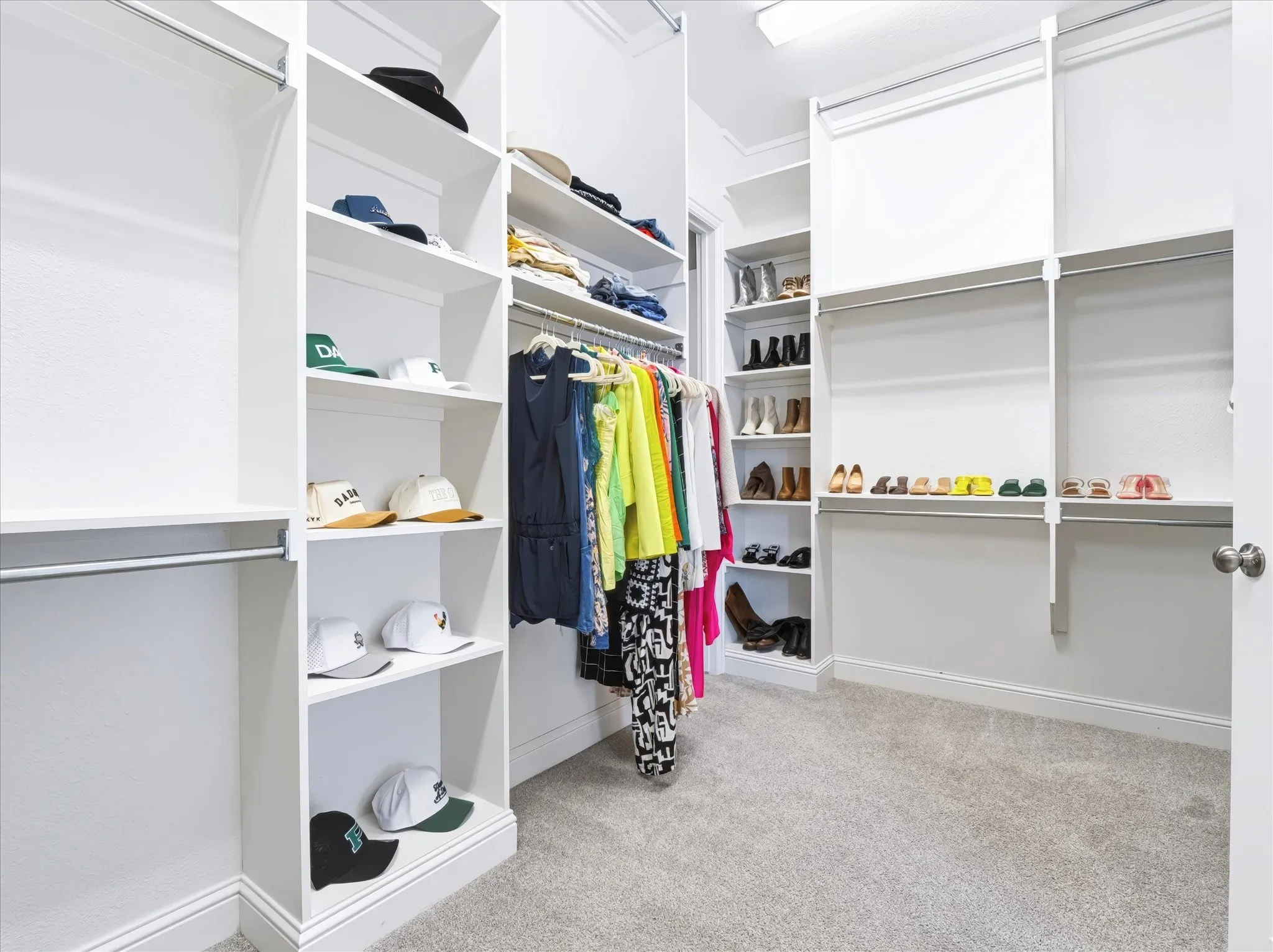 Custom white built-in shelving, multiple hanging rods, and light gray carpeting