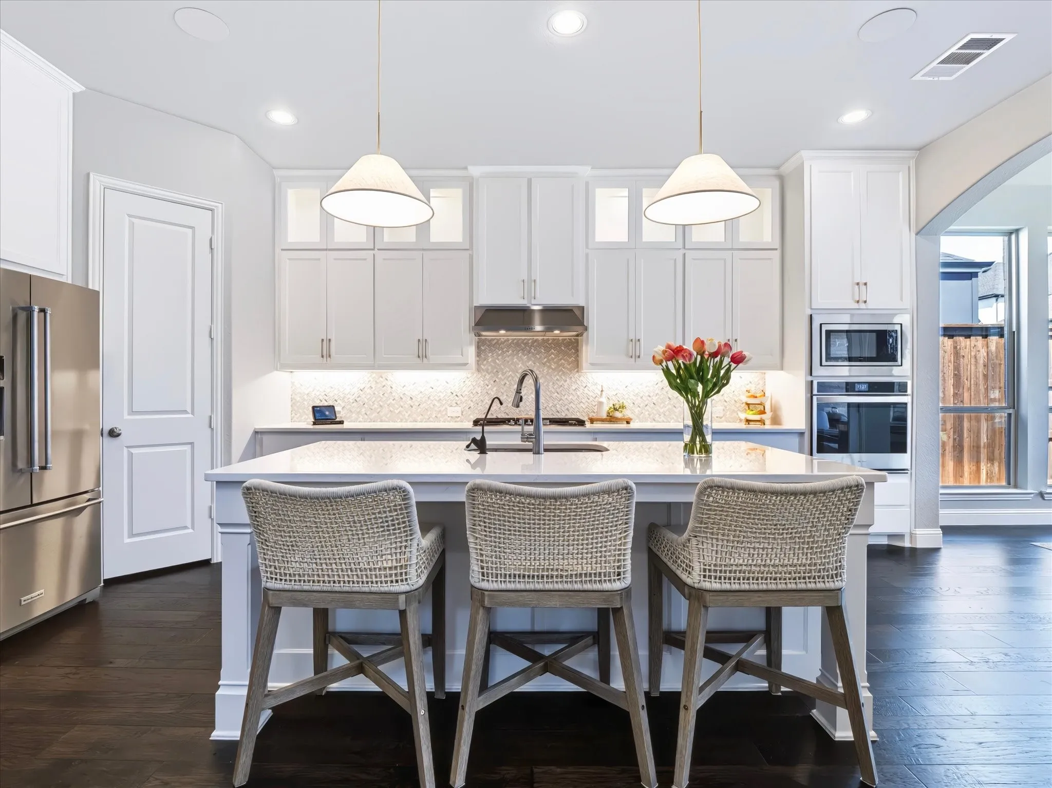Kitchen featuring a central island with a sink, stainless steel appliances, white cabinetry, recessed lighting, and dark wood-finish flooring
